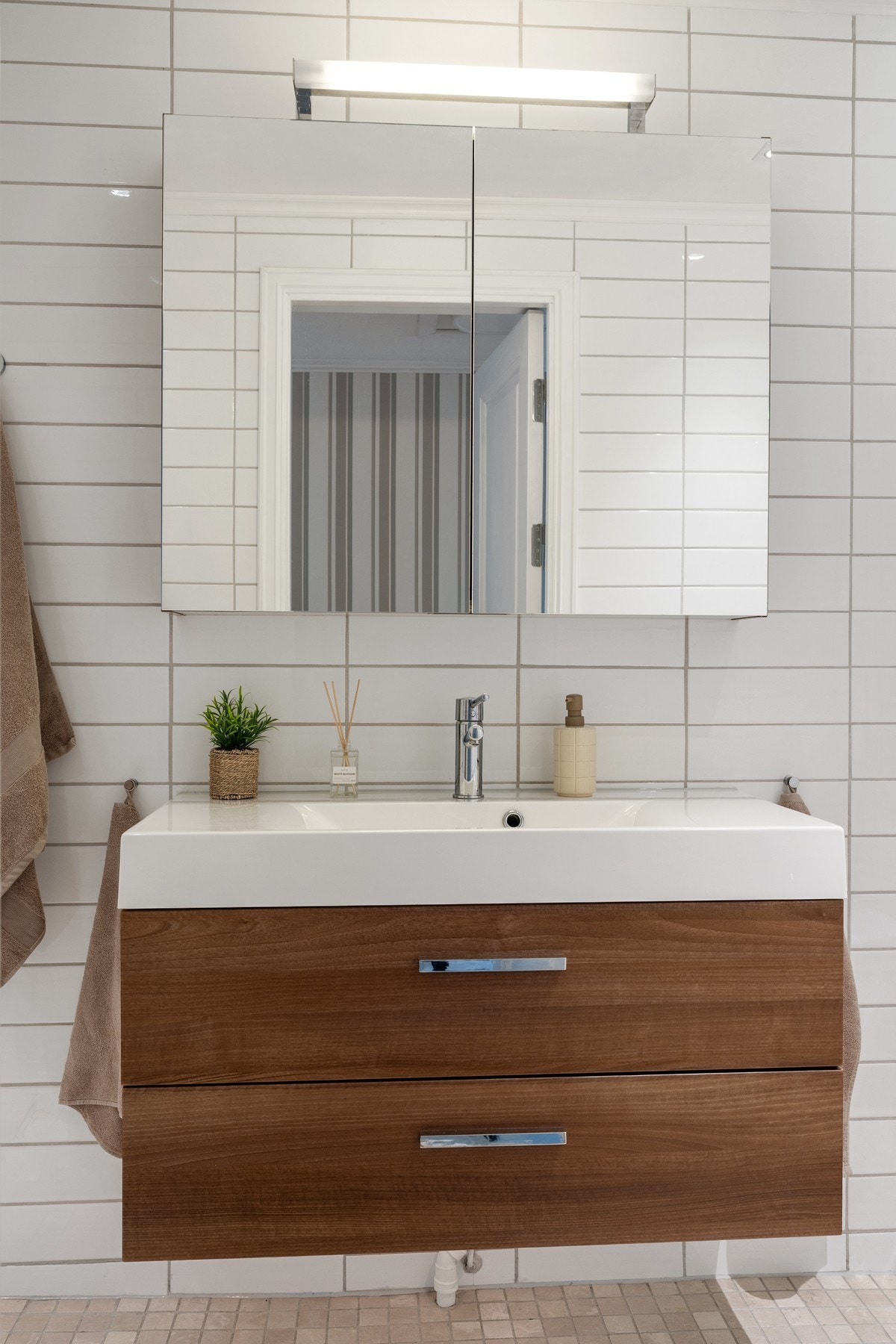 Badet er innredet med vegghengt servantinnredning med ovenpåliggende servant, samt speilskap med overlys over servanten. Galleribilde