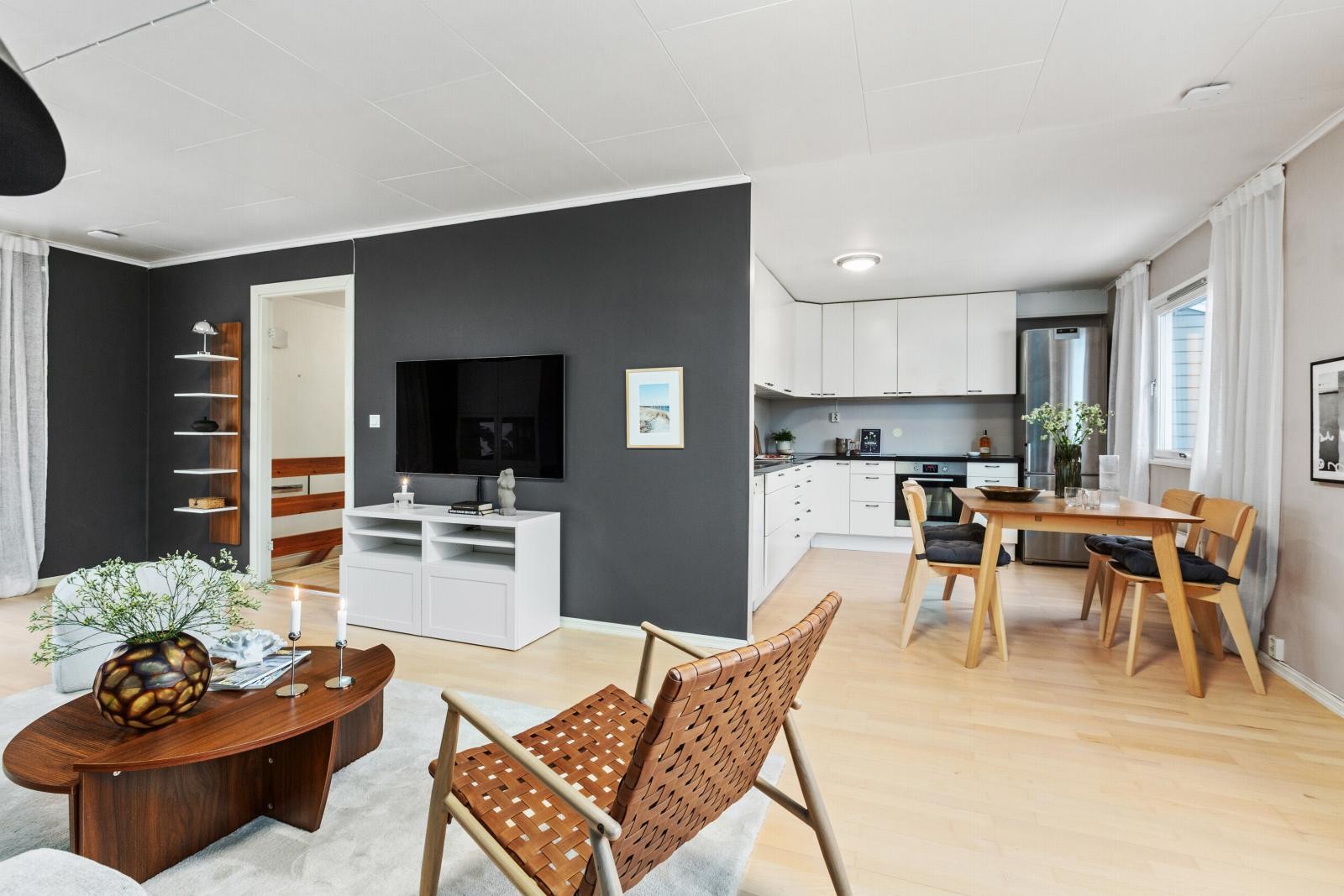 Rommet har lys parkett, mørk kontrastvegg og en åpen løsning mot kjøkken. Galleribilde