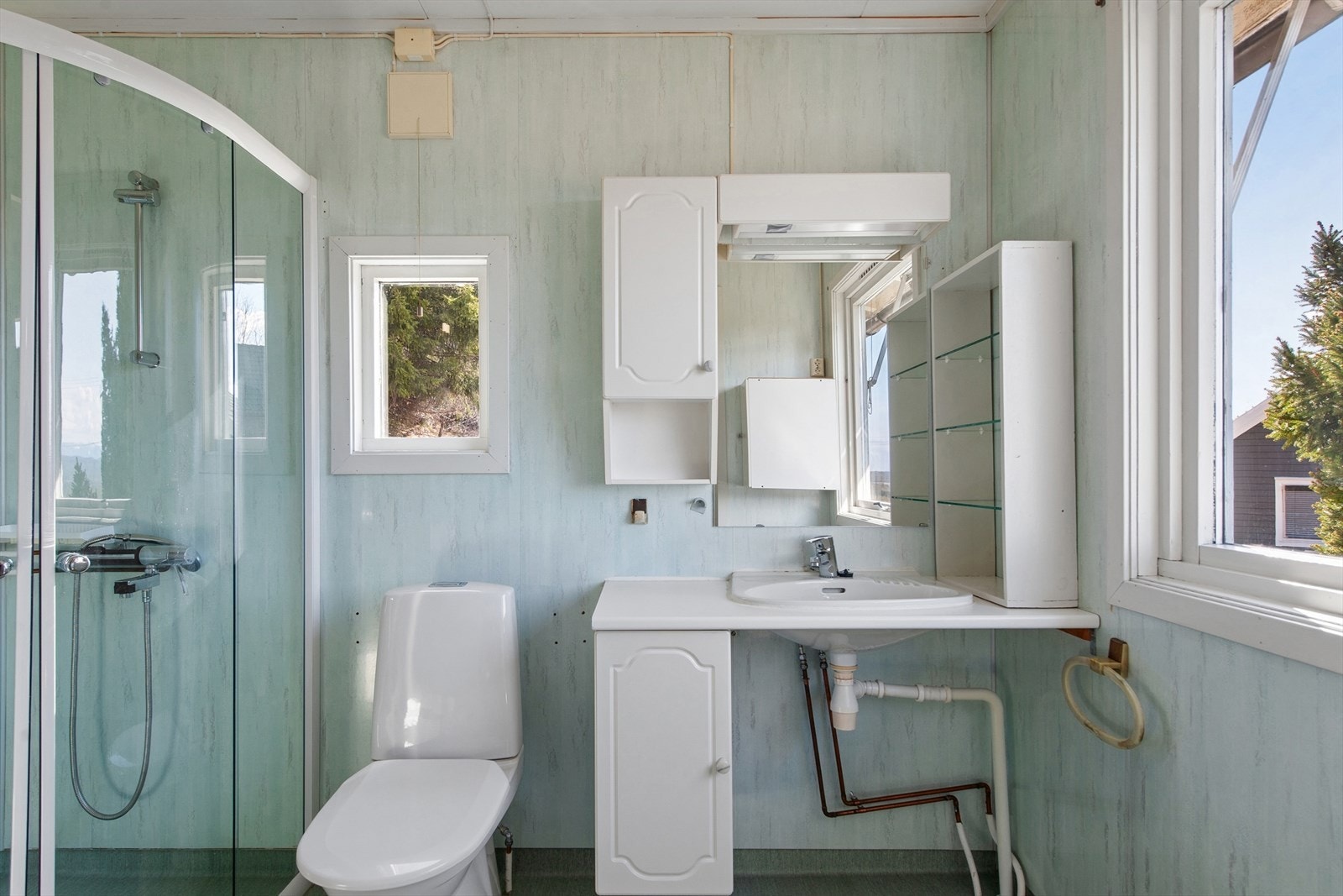 Badet er innredet med ett-greps blandebatteri, toalett og veggmontert dusj i dusjkabinett med glassdører. Det er også opplegg for vaskemaskin. Galleribilde