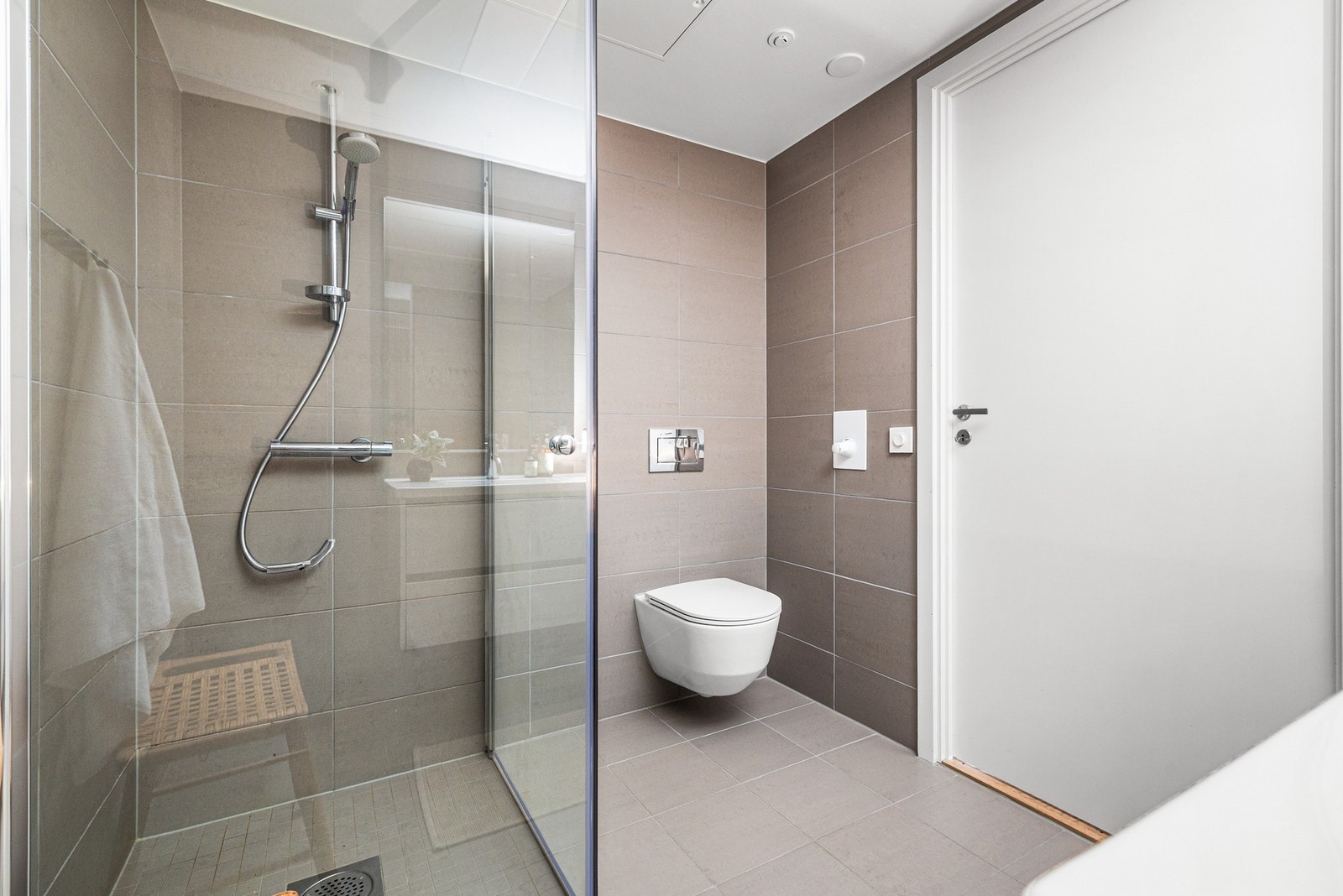 Badet er utstyrt med dusjnisje med glassdører, vegghengt toalett og servant med innredning. Opplegg for vaskemaskin og vannbåren varme i gulv. Galleribilde