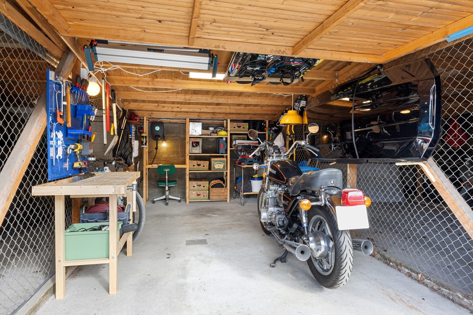 Romslig garasje med god plass til både bil, motorsykkel og oppbevaring, samt praktisk arbeidsbenk for hobby og vedlikehold. Galleribilde