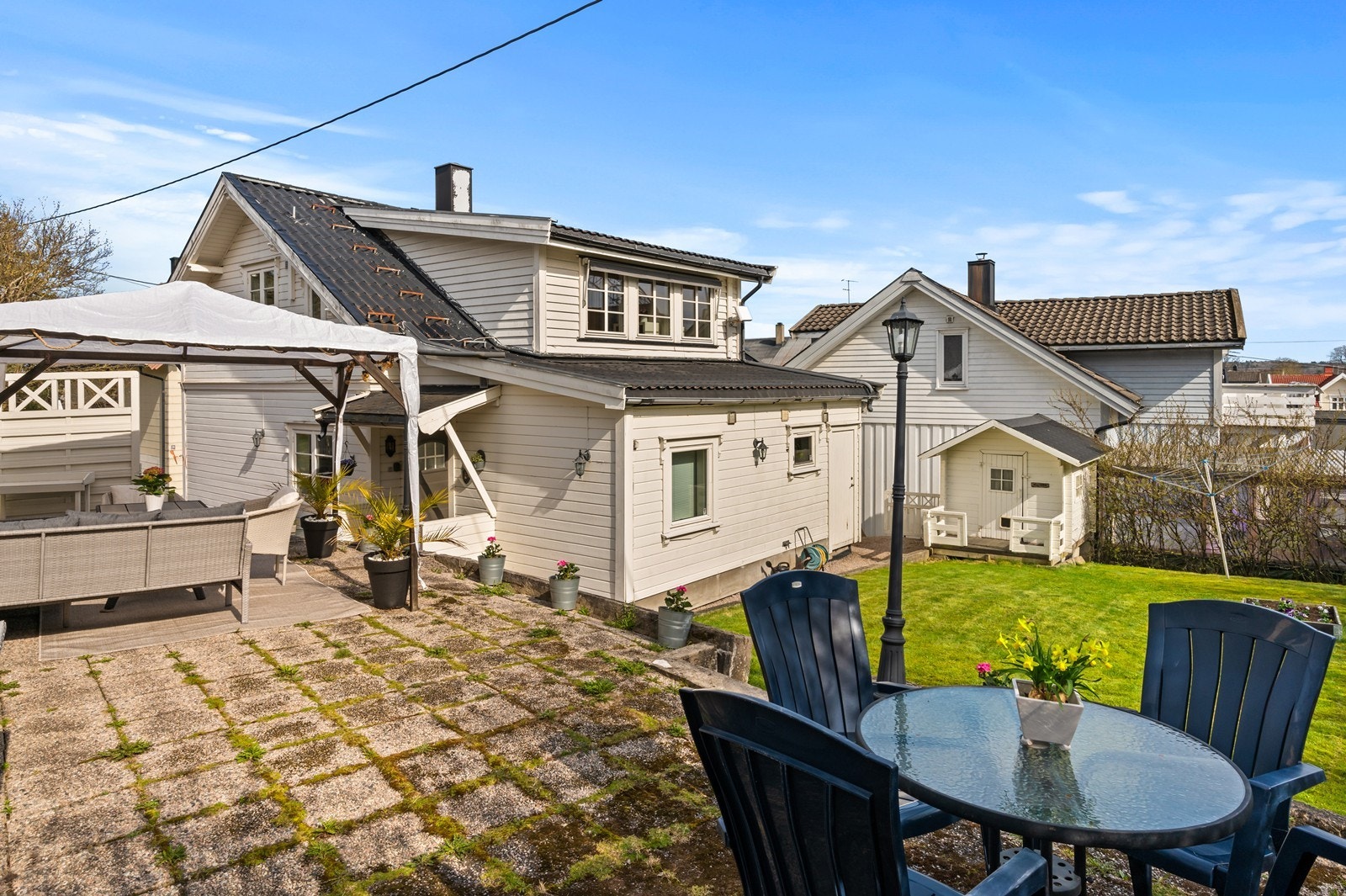 Eiendommen ligger på en skrånende tomt med en opparbeidet hage og flere soner for uteplasser. Galleribilde