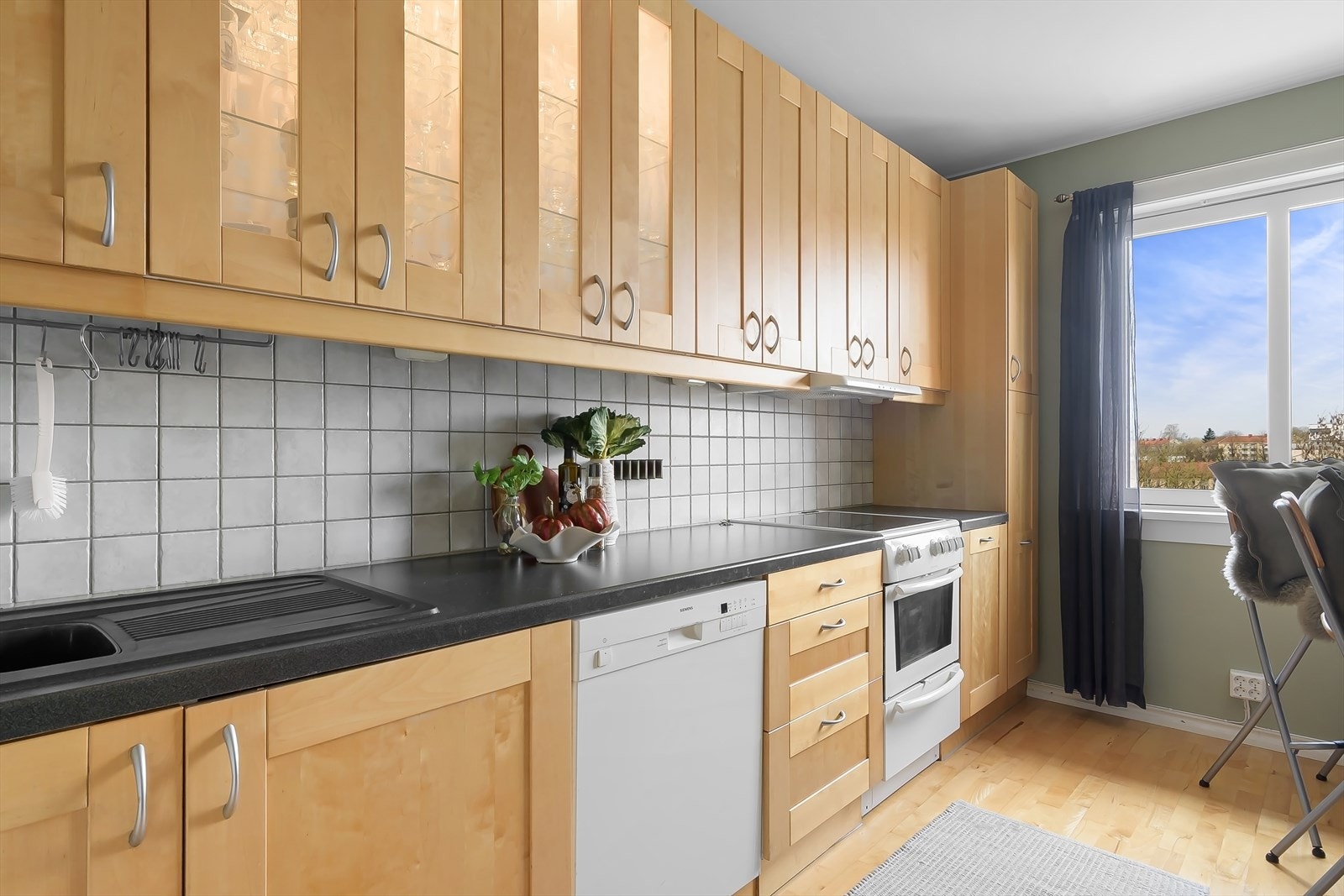 Kjøkkenet ligger praktisk separat fra stuen. Pen innredningen har profilerte heltre fronter og laminat benkeplate som gir gode arbeidsflater. Fliser på bakvegg gjør det enkelt å holde rent. Galleribilde