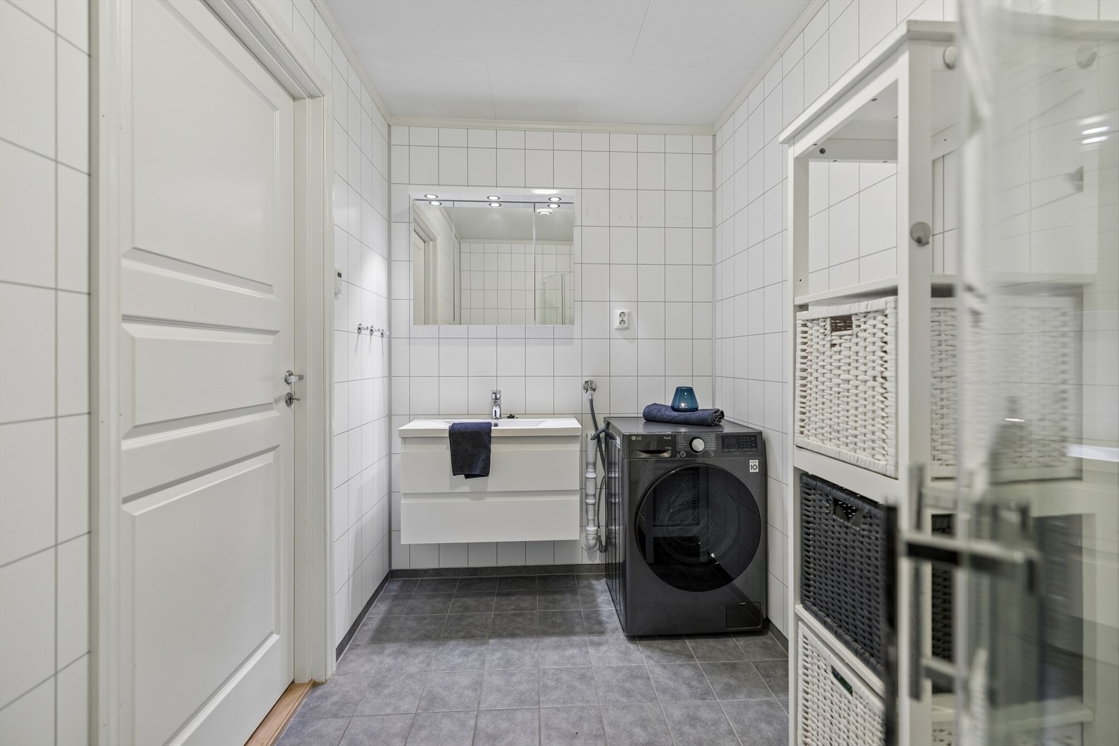 Baderomsinnredning med slette fronter, heldekkende servant og speilskap med belysning. Galleribilde