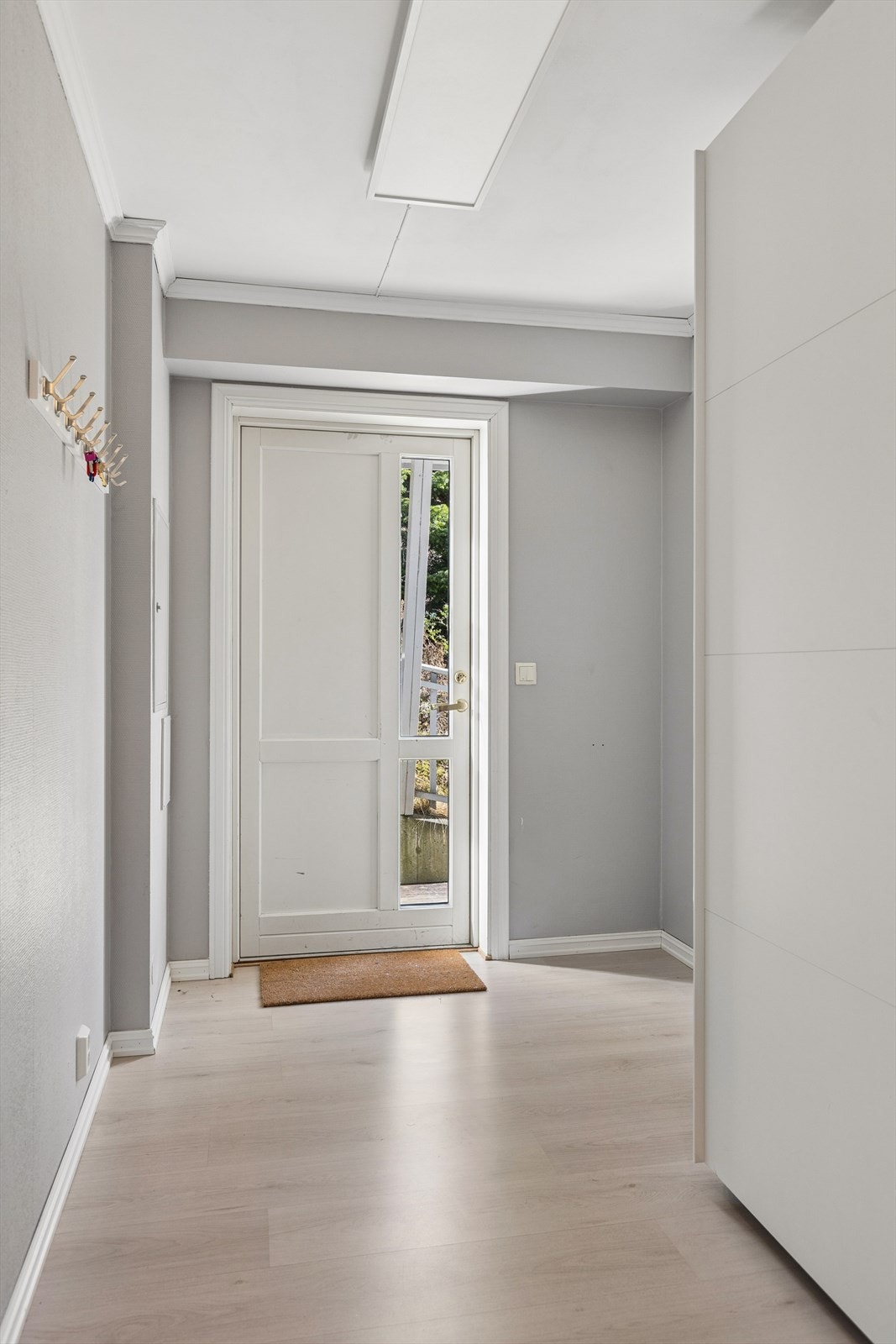 Romslig entré med gode lagringsmuligheter for yttertøy og sko i en praktisk skyvedørsgarderobe Galleribilde