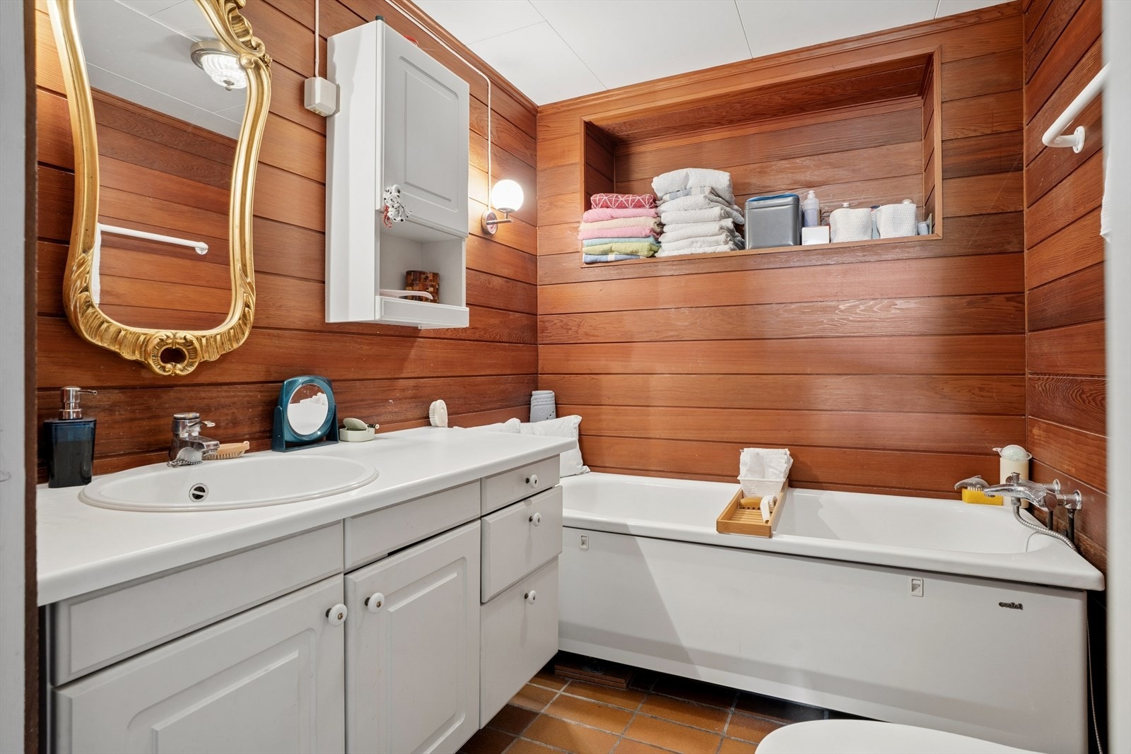 Badet i underetasjen er fra 1980 og har en sjarmerende stil med flislagt gulv, vegger i redwoodpanel og badekar. Galleribilde