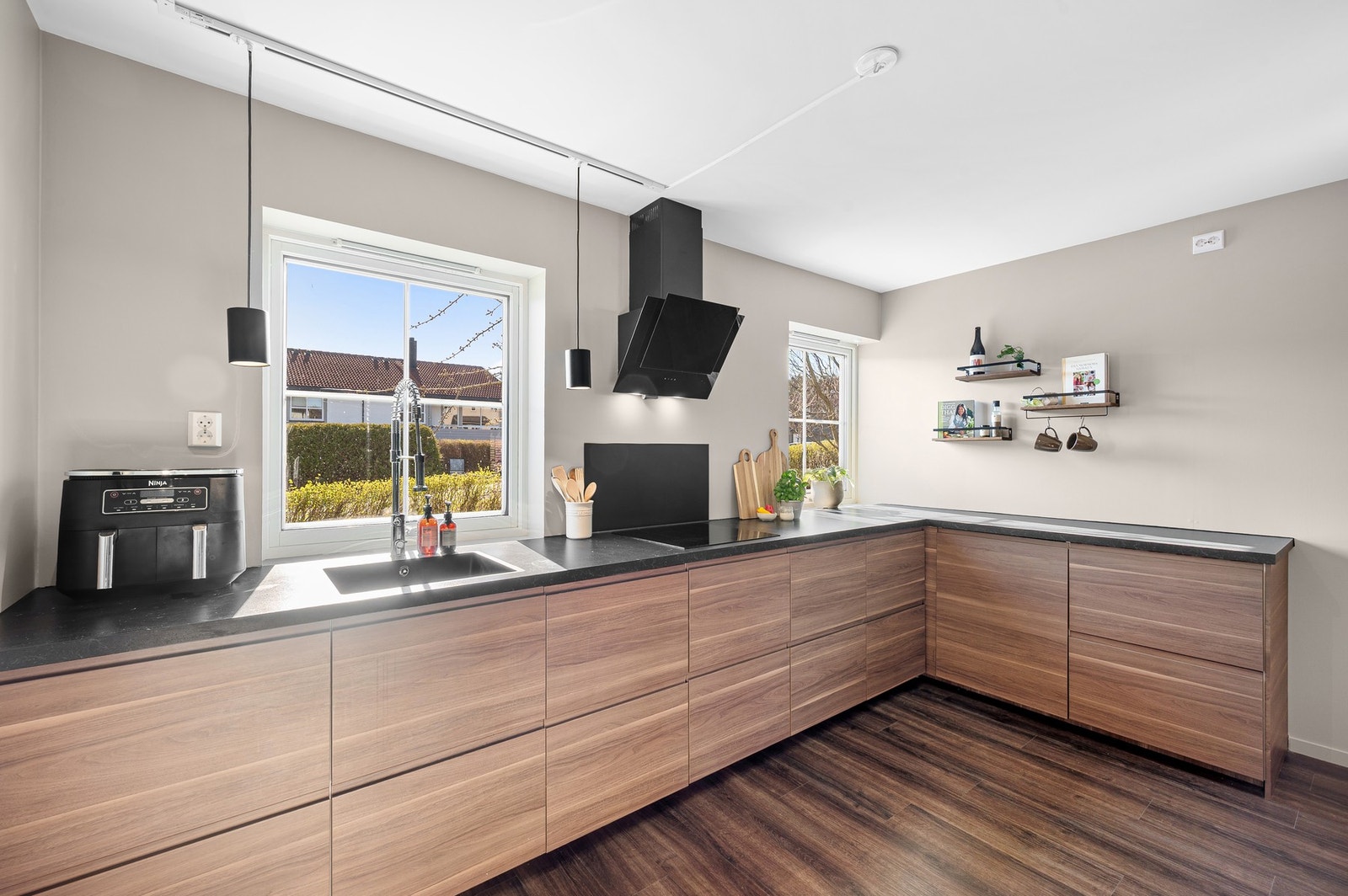 Kjøkkeninnredning med integrert platetopp, stekeovn, oppvaskmaskin, kaffemaskin, kjøleskap og fryseskap. Galleribilde