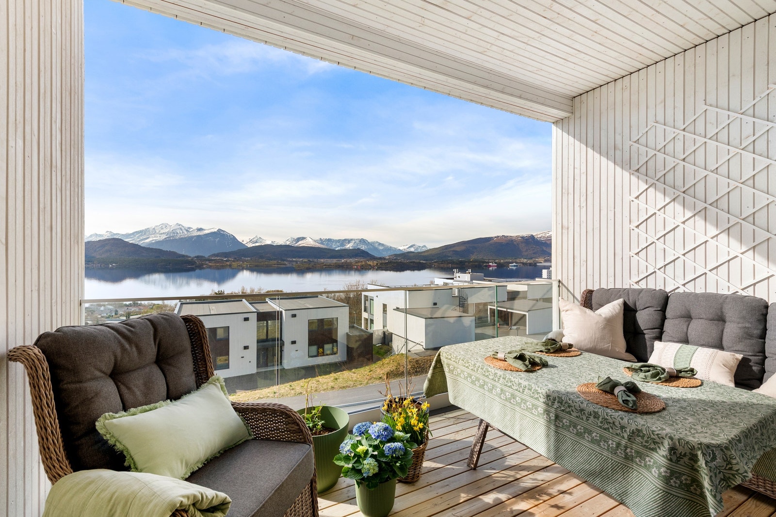 Balkongen har terrassebord på gulvet, rekkverk i glass og metall, samt utelys og stikkontakt Galleribilde