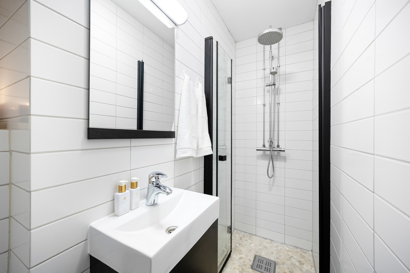 Badet er innredet med vegghengt servantskap med ovenpåliggende vask og speil med belysning. Galleribilde