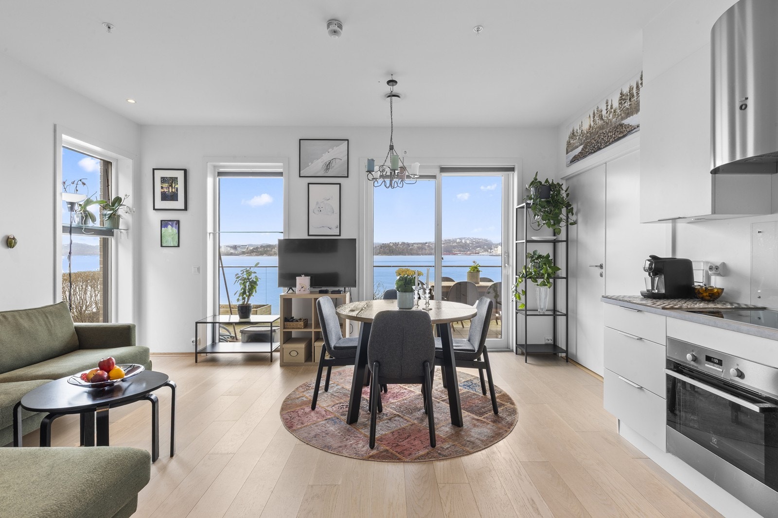 Stuen er lys og romslig, med store vindusflater som gir godt med naturlig lys og åpen utsikt mot uteplassen og sjøen. Galleribilde