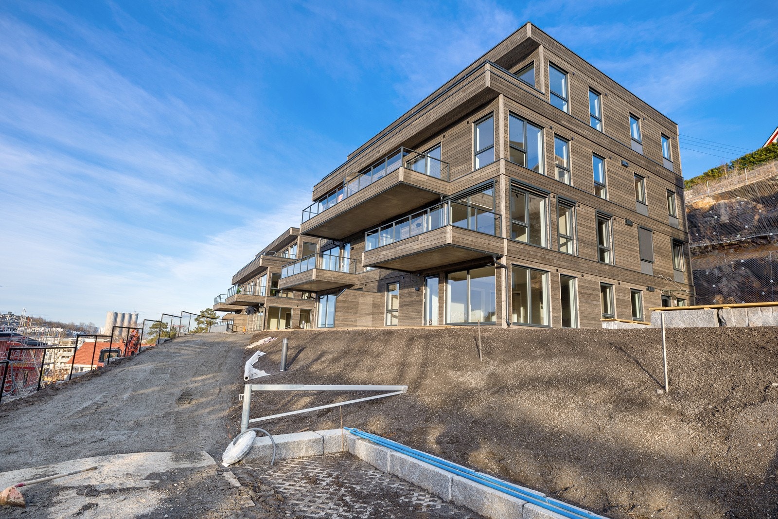 Moderne arkitektur med trepanel i gråtoner og romslige terrasser i toppetasjen. Galleribilde