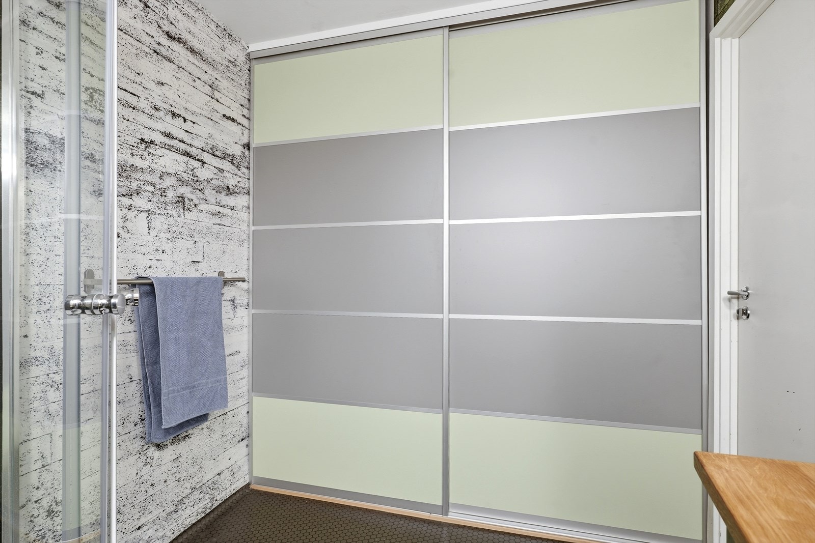 En stor skyvedørsgarderobe på badet gir rikelig med skjult oppbevaring og rommer opplegg for vaskemaskin. Galleribilde
