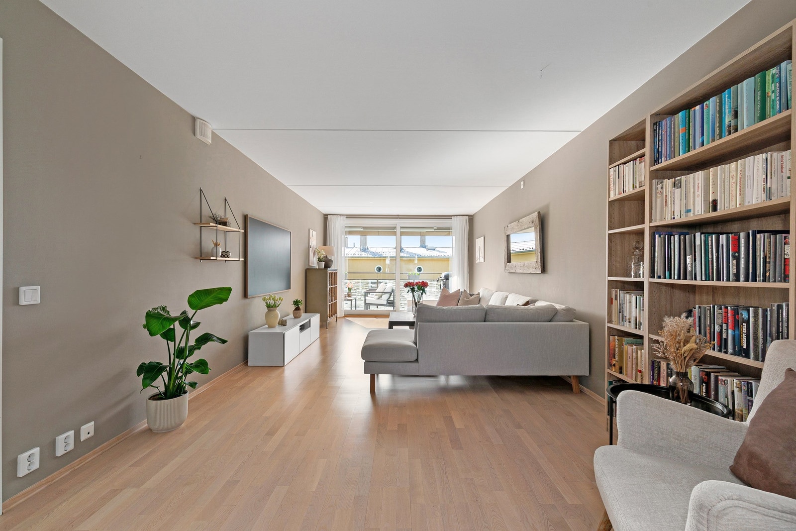 Stuen er romslig og enkel å møblere, med plass til en stor sofa og en sittegruppe. Det gjennomgående parkettgulvet gir leiligheten et moderne og helhetlig preg Galleribilde