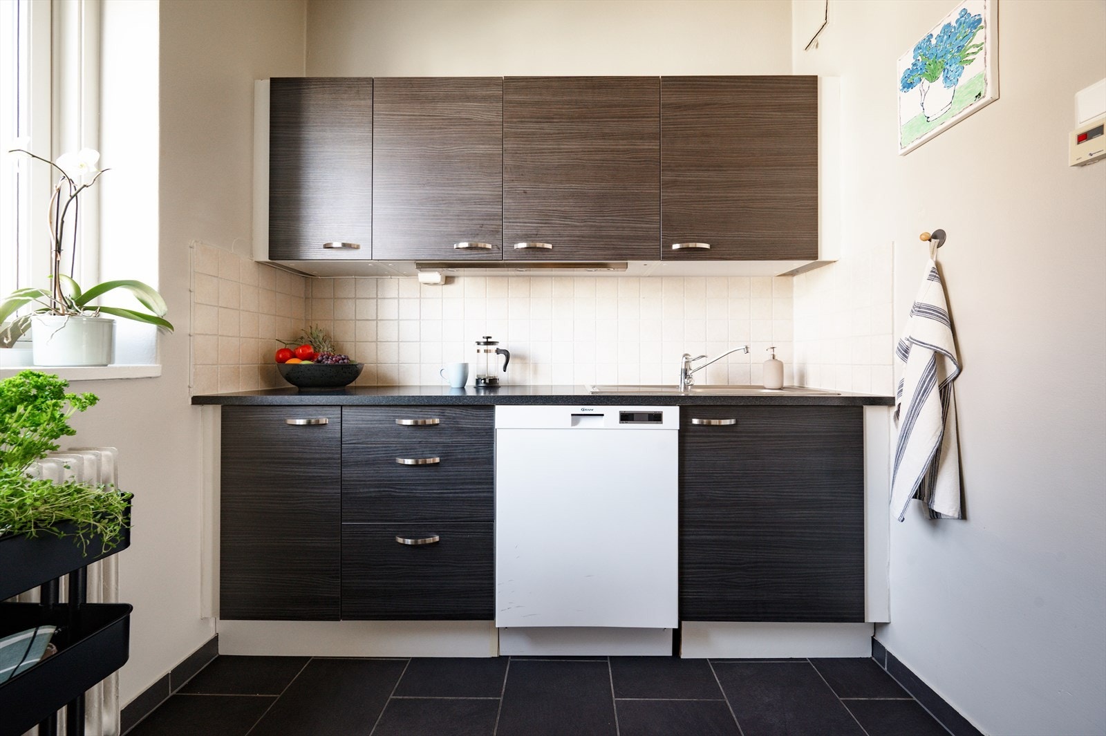 Benkeplate i laminat med nedfelt vask og ettgreps blandebatteri. Det er opplegg for vaskemaskin, samt plass til frittstående hvitevarer. Galleribilde