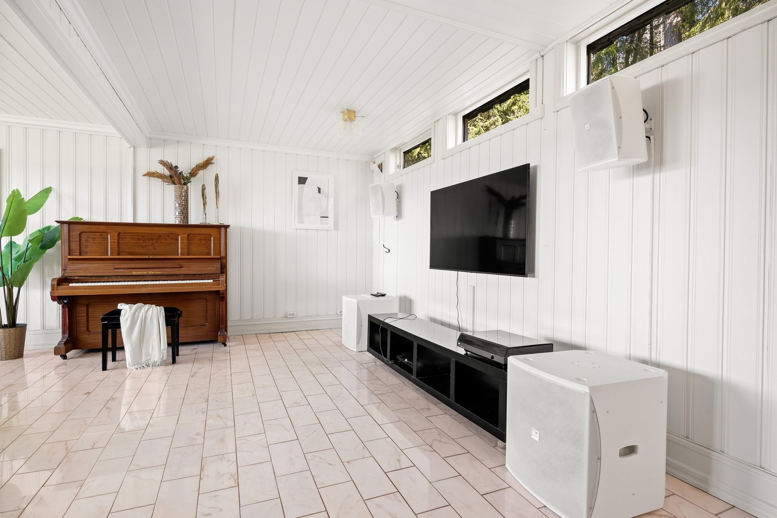 Lyst rom med hvite vegger og tak, store vinduer og flislagt gulv. Galleribilde