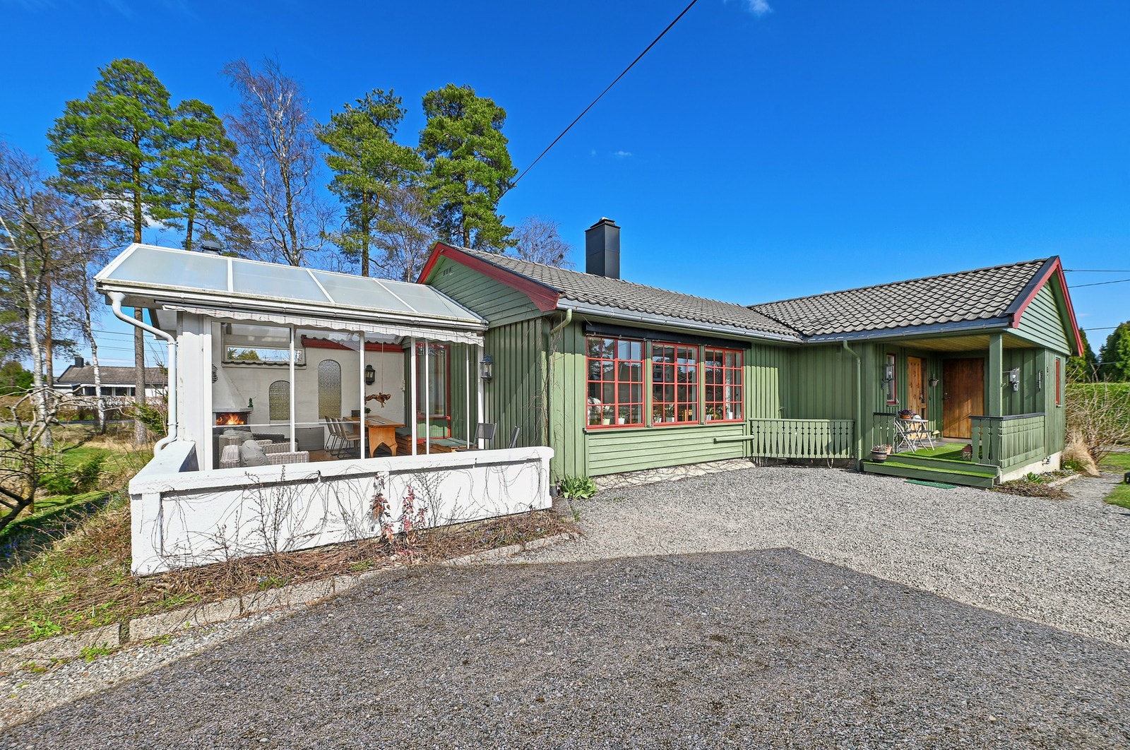 Grønn enebolig med vinterhage og gruslagt gårdsplass. Galleribilde