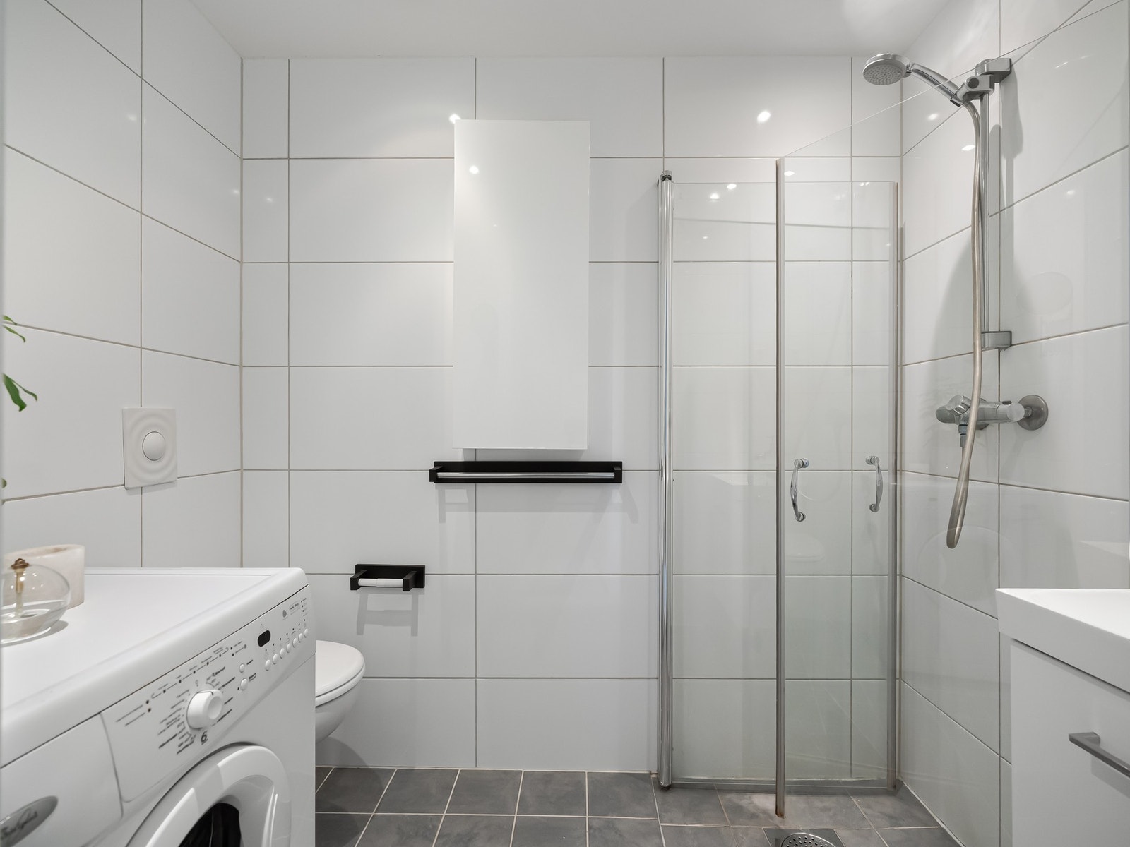 Badet er innredet med servantskap med oppbevaring, speil på vegg, toalett og dusjsone med glassdører. Galleribilde