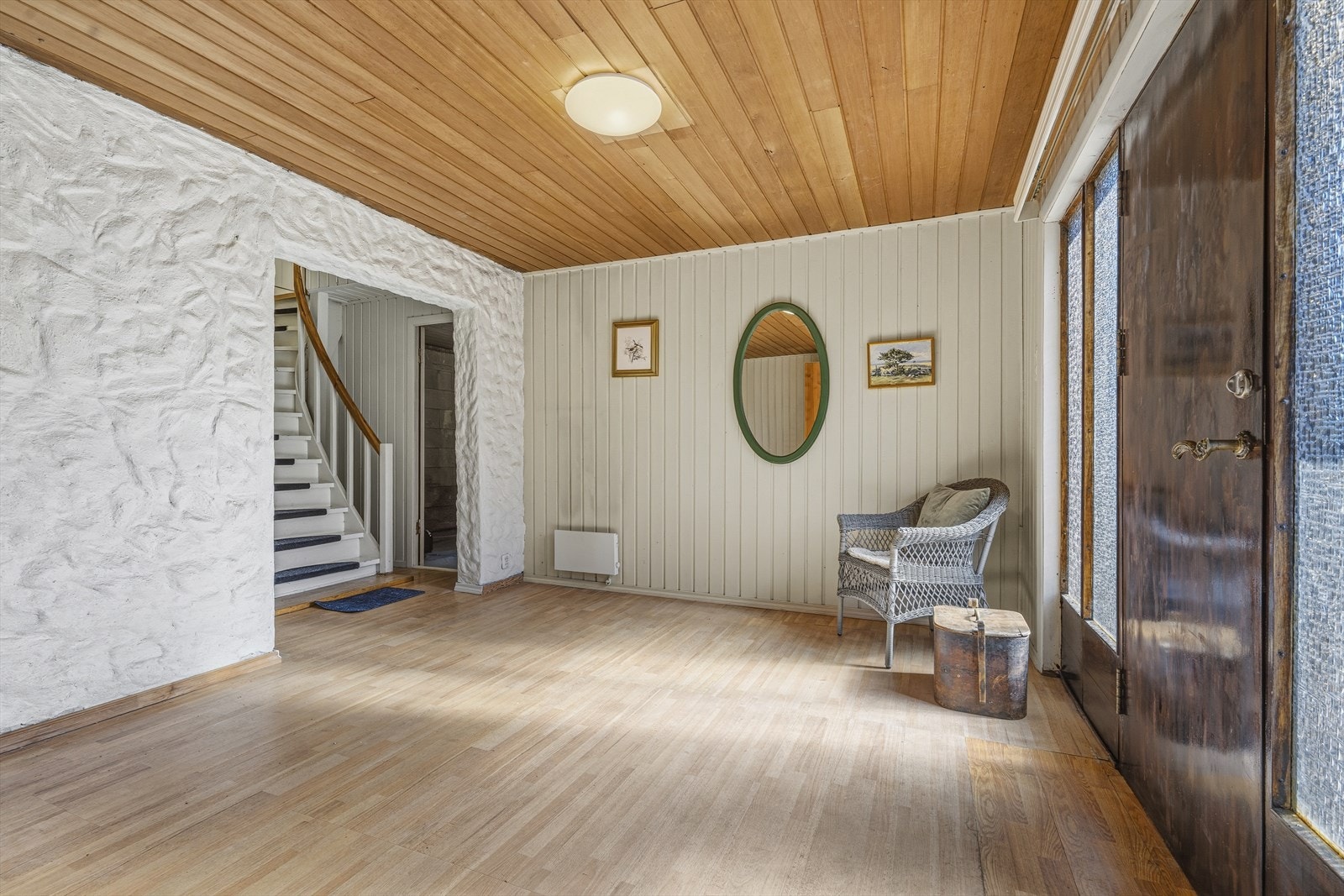 Romslig entré i kjelleretasjen med laminat på gulv og panel på vegger. Herfra fører trappen deg opp til hovedetasjen. Galleribilde