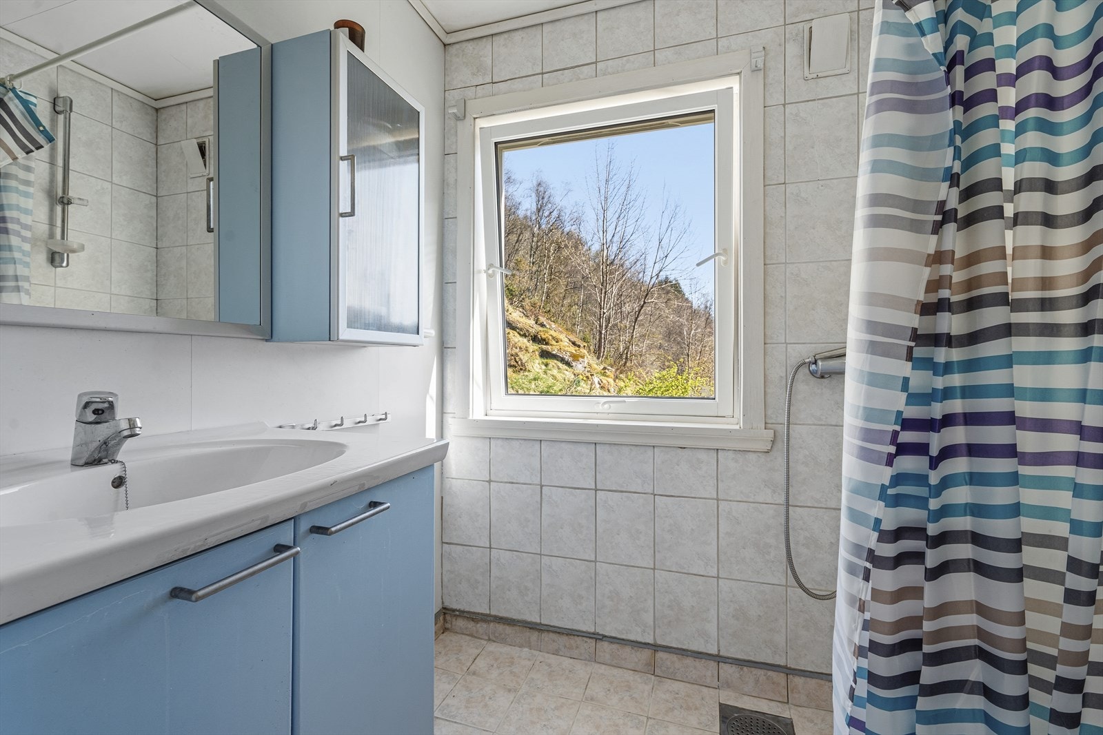 Badet i hovedetasjen har varmekabler i gulvet, flislagte vegger og dusj med forheng. Galleribilde