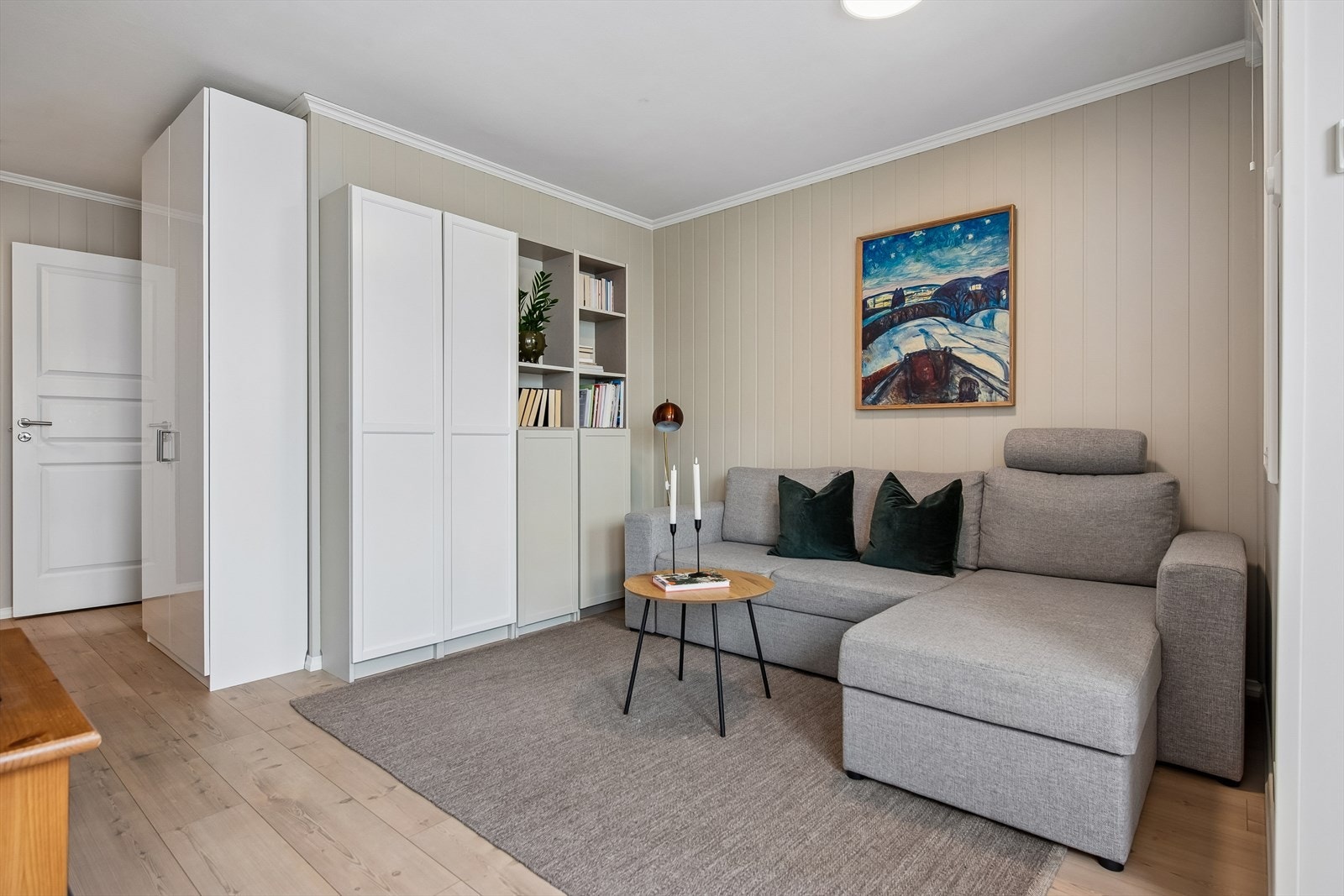 Panelplater på veggene gir rommet en lun og helhetlig karakter. Overflatene i leiligheten ble oppgradert i 2012. Galleribilde