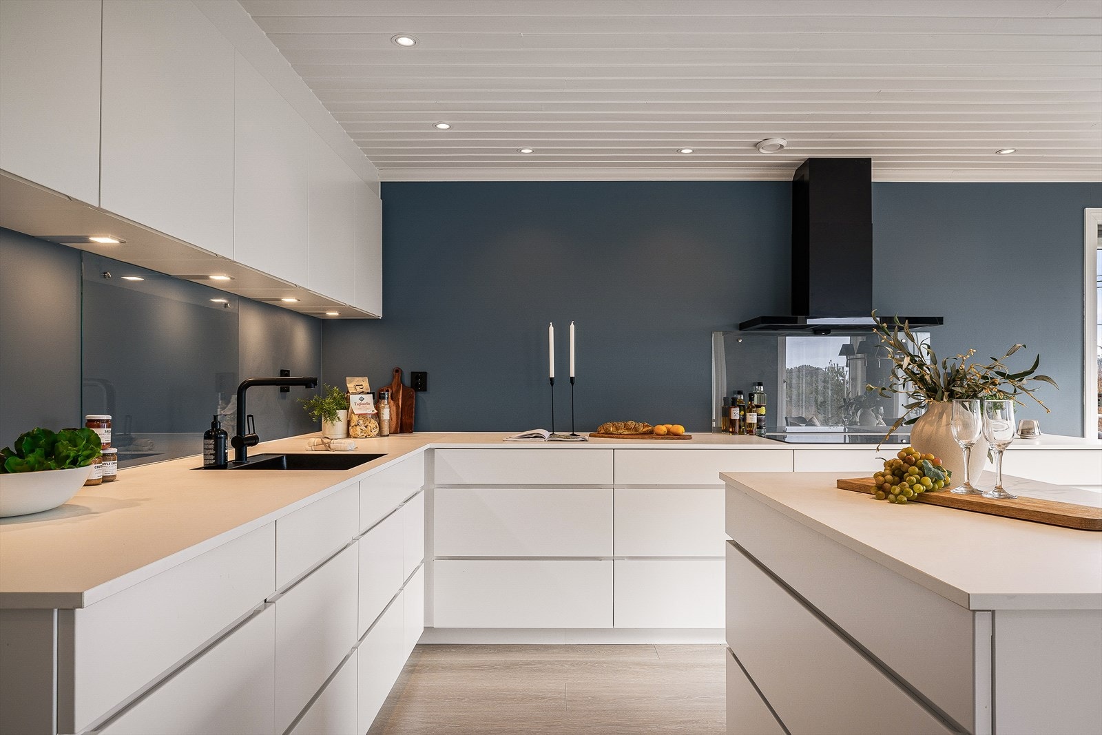 To glassplater over benkeplate og belysning/stikk under overskap. Induksjonstopp (80 cm) fra Bosch og integrert oppvaskmaskin fra Siemens. Galleribilde