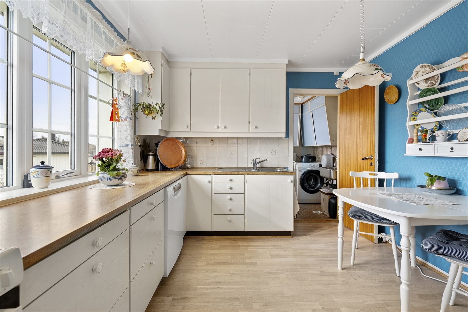Kjøkkenet har malte fronter med lett profilering og laminat benkeplate med dobbel stålvask. Veggene over benken er flislagt. Galleribilde