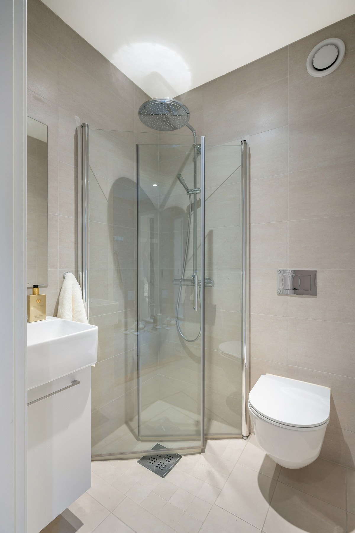 Badet i første etasje er innredet med servant med underskap, vegghengt toalett og dusjhjørne/dører i glass. Flislagte vegger og gulv med varmekabler, samt malt himling med innfelte downlights. Galleribilde