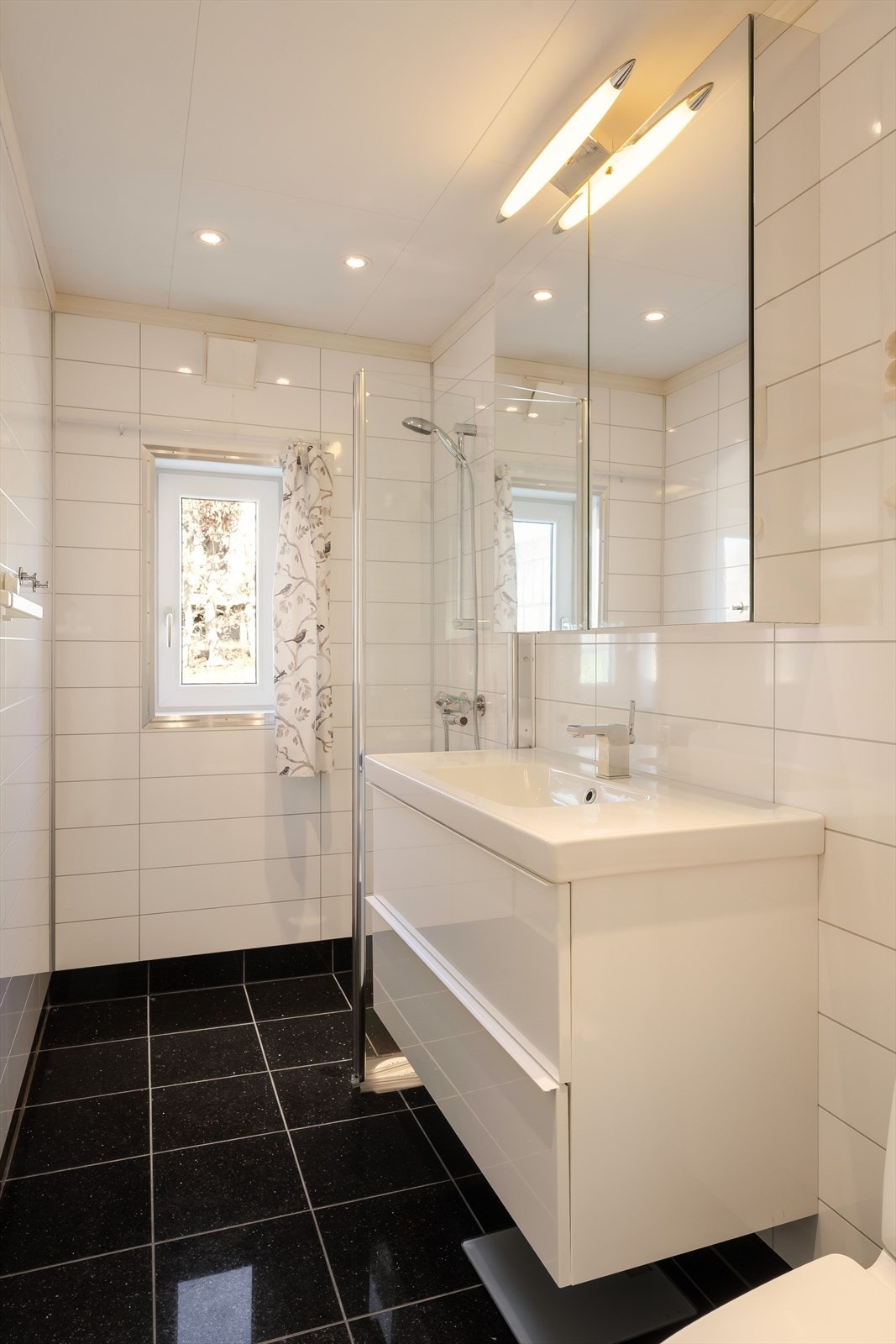 Badet i hovedetasjen ble modernisert i 2011/12 av tidligere eier, og består av granittfliser på gulv, baderomsplater på vegger og takplater m/led spotlights i himling. Rommet inneholder servant m/møblement, toalett, innfellbart dusjdør & dusjgarnityr. Galleribilde