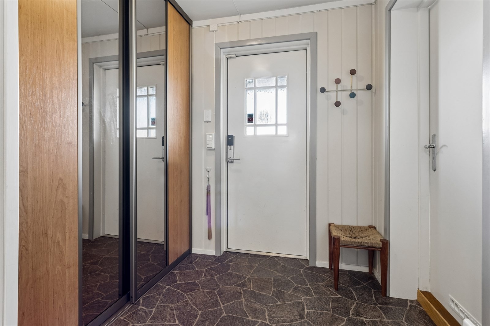Entréen ønsker velkommen med god plass til oppbevaring i garderoberom bak skyvedørene, og elektrisk gulvvarme. Galleribilde