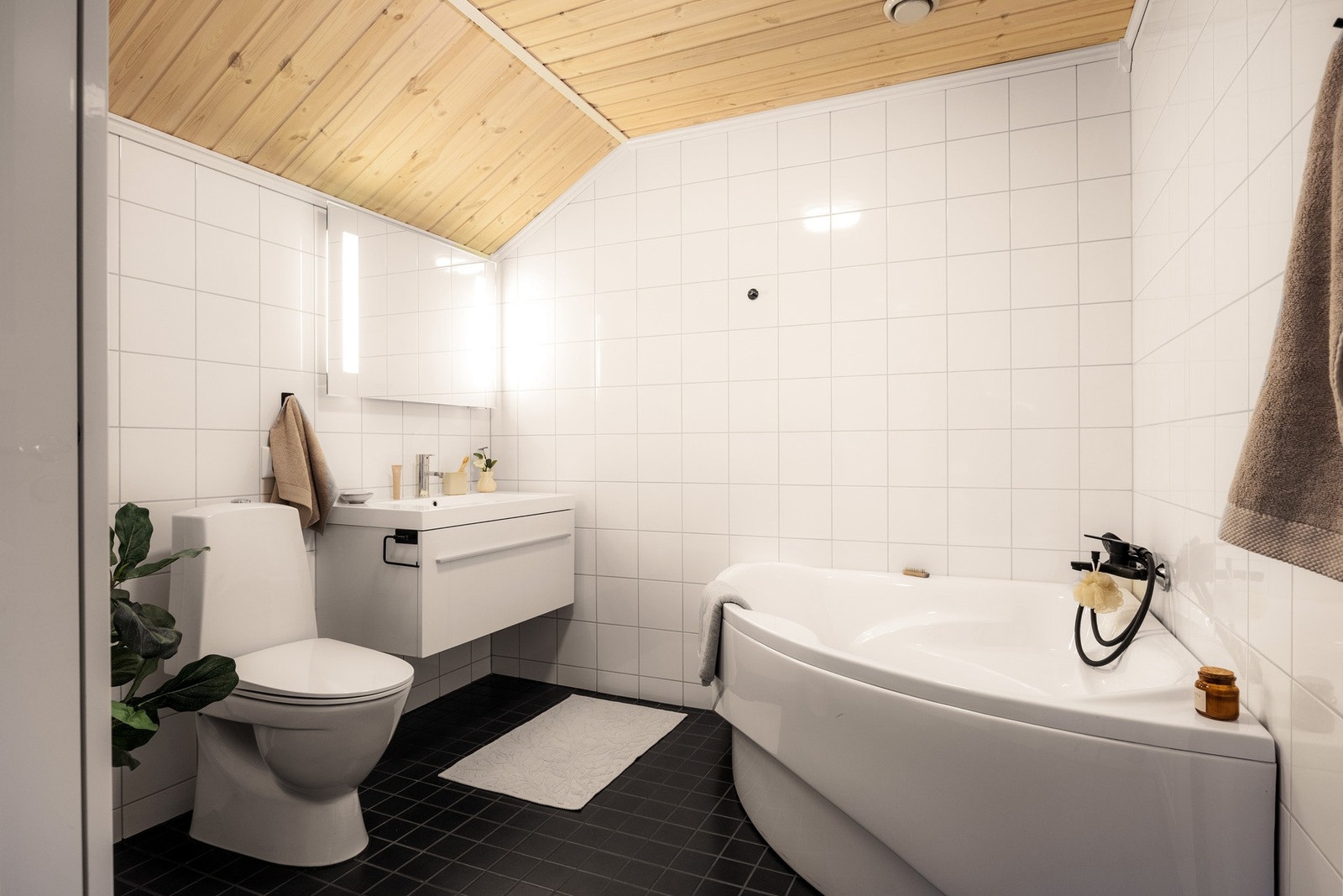 Badet i loftsetasjen er også flislagt og fremstår med WC, servant i innredning og badekar, perfekt for rolige kvelder og litt ekstra hverdagsluksus. Galleribilde