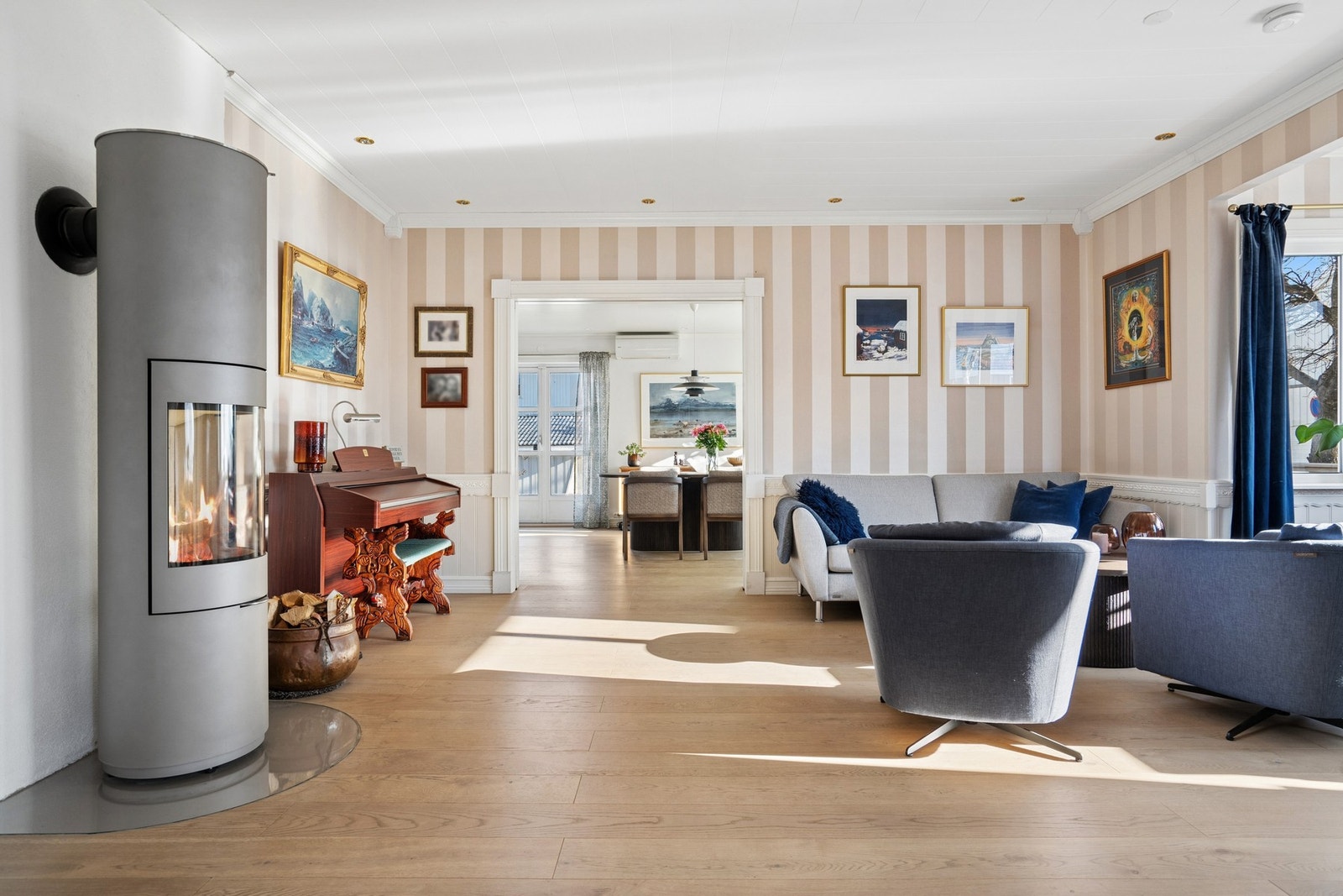 Fra den ene stuen er det åpent inn mot den andre, hvor en moderne vedovn er plassert. Galleribilde