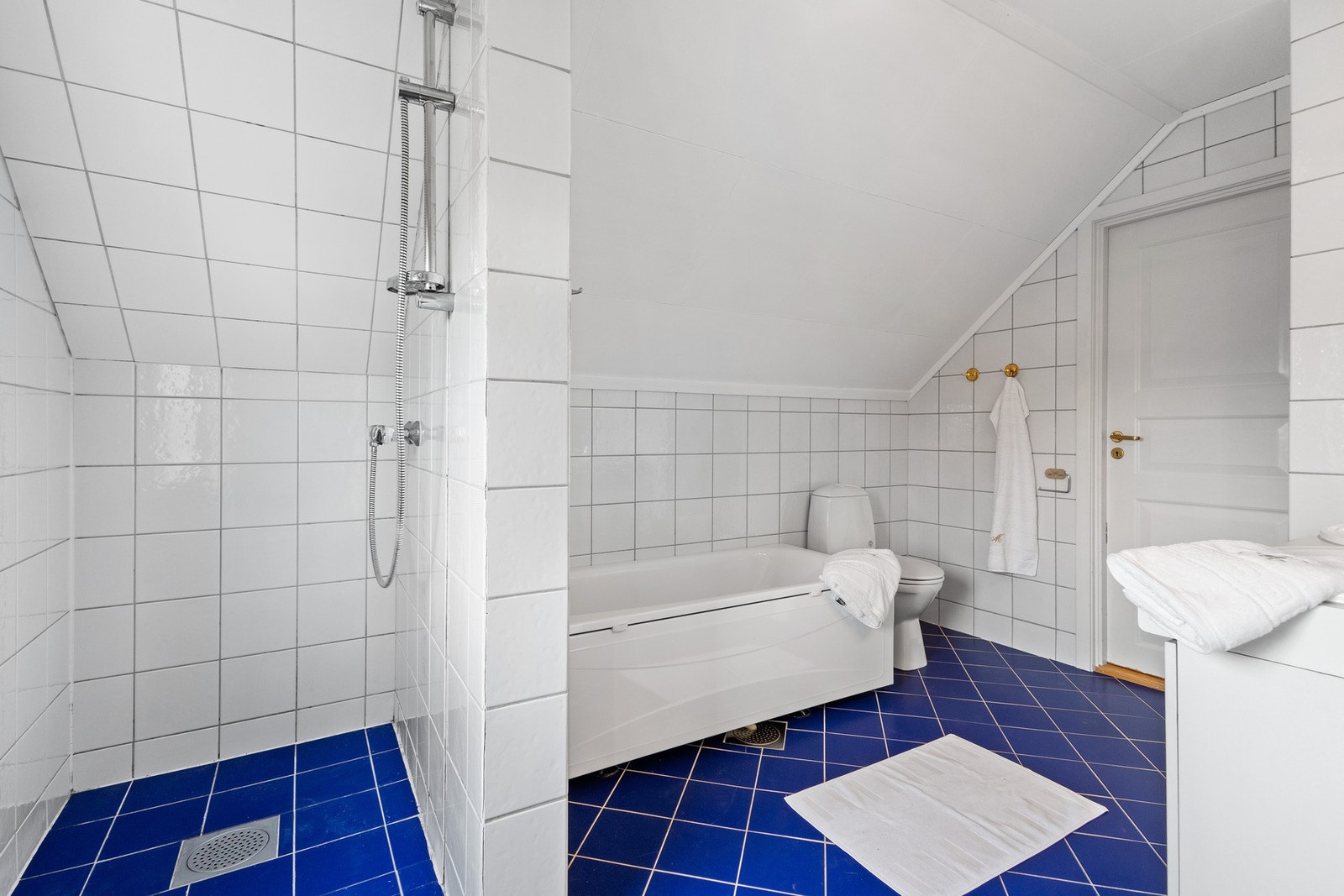 Flislagt baderom innredet med badekar, servant med servantskap og klosett. Galleribilde