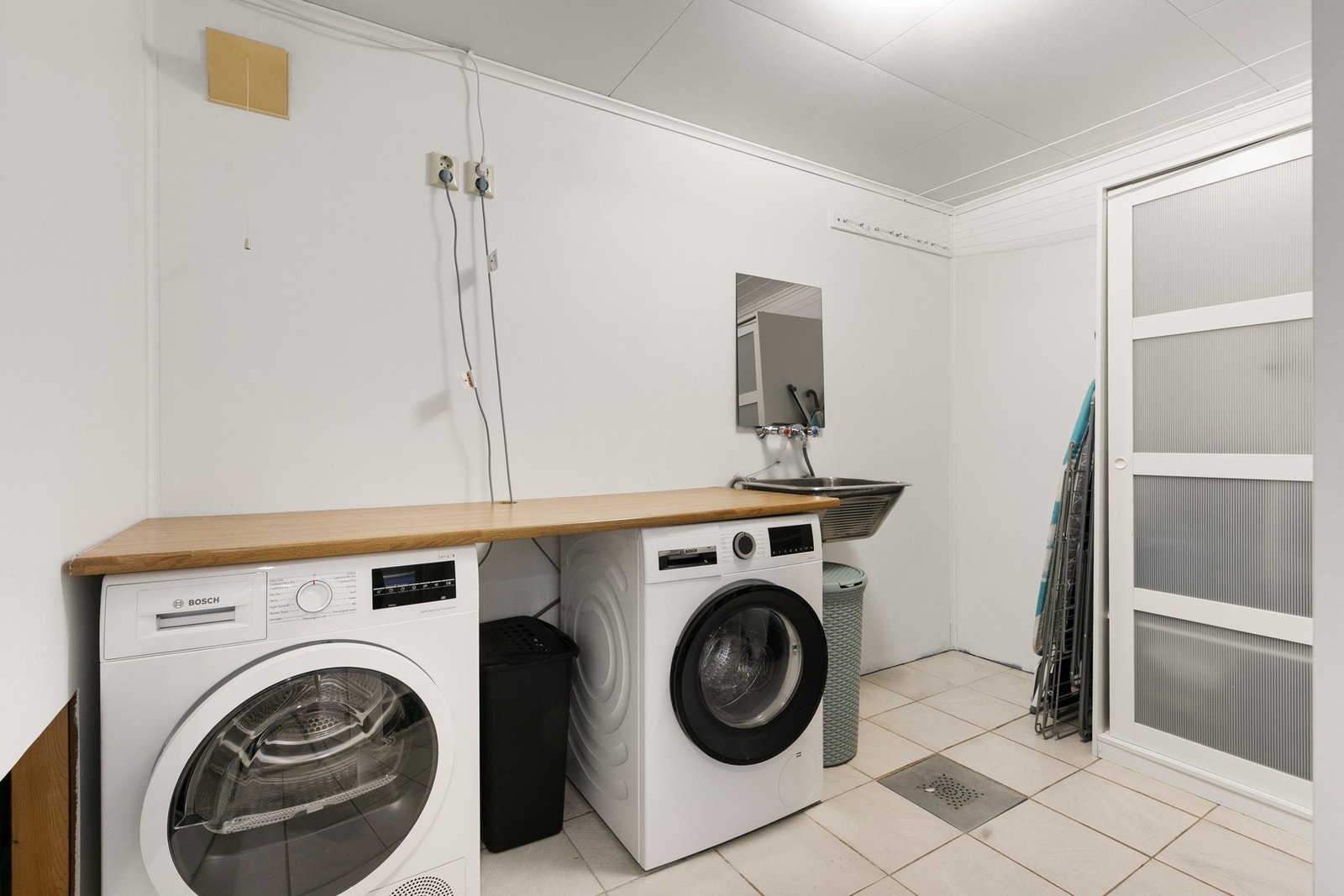 Vaskerom med flislagt gulv, utslagsvask og opplegg for vaskemaskin. Galleribilde