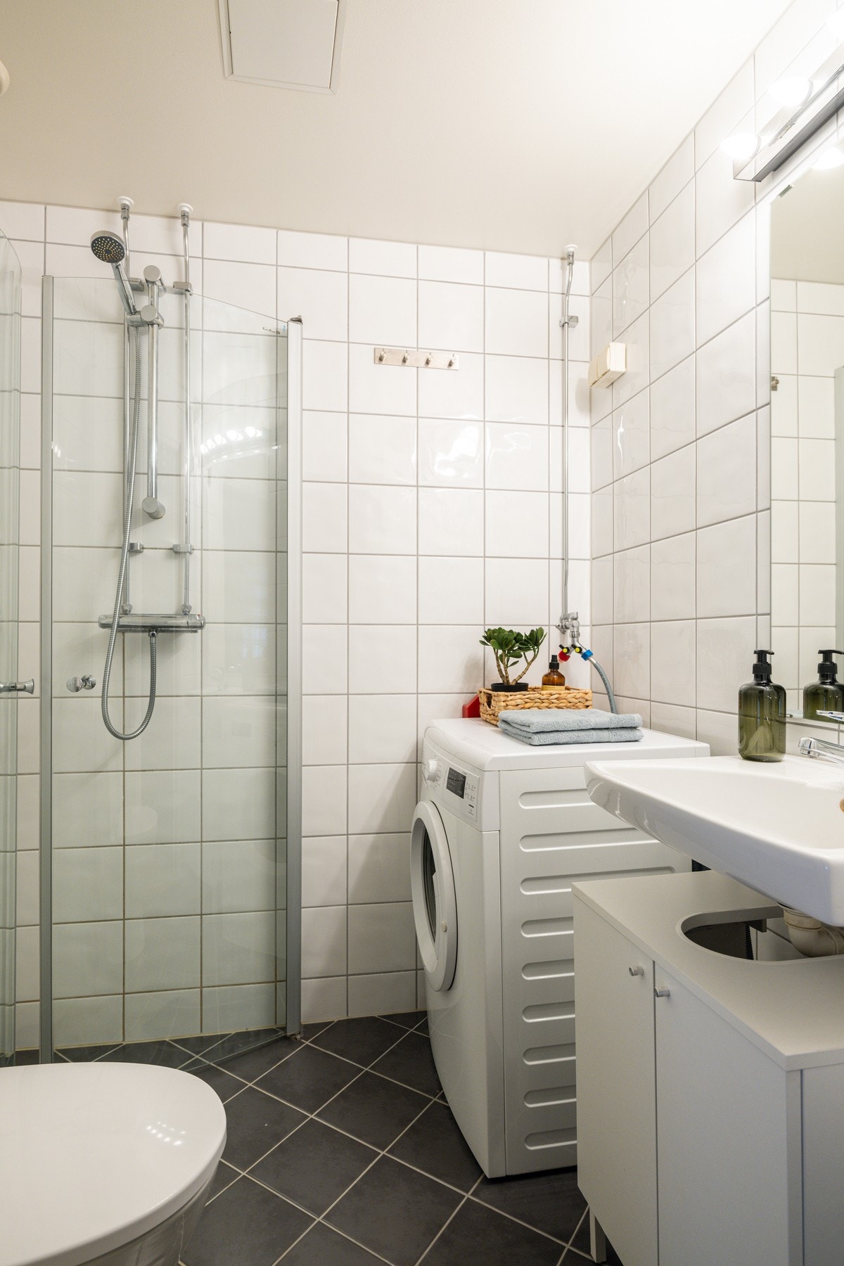 Tidløst flislagt bad med opplegg for vaskemaskin. Bad i regi av aksjelaget. Galleribilde