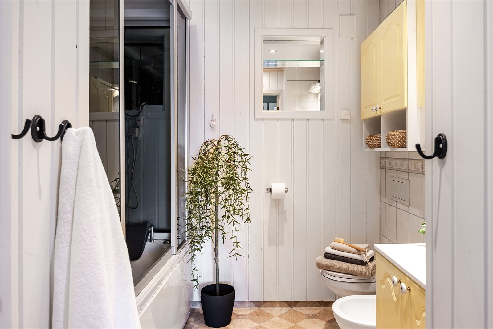 Badet har vegger med både panel og fliser, mens gulvet har belegg med vannbåren gulvvarme. Galleribilde