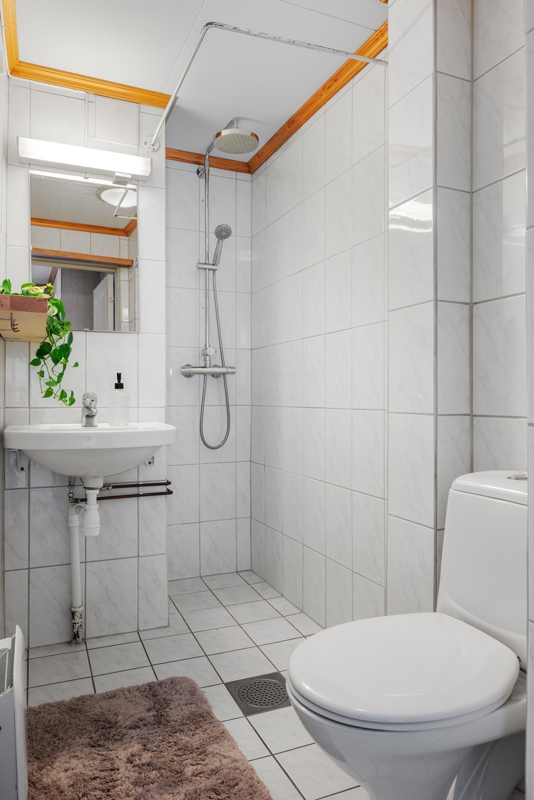 Badet er helfliset, innredet med toalett, panelovn og åpent dusjhjørne. Galleribilde