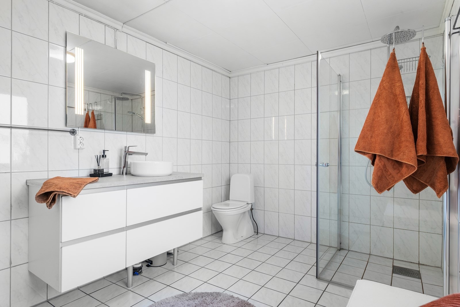 Den moderne baderomsinnredningen har god plass til oppbevaring av håndklær og hygieneartikler. Galleribilde