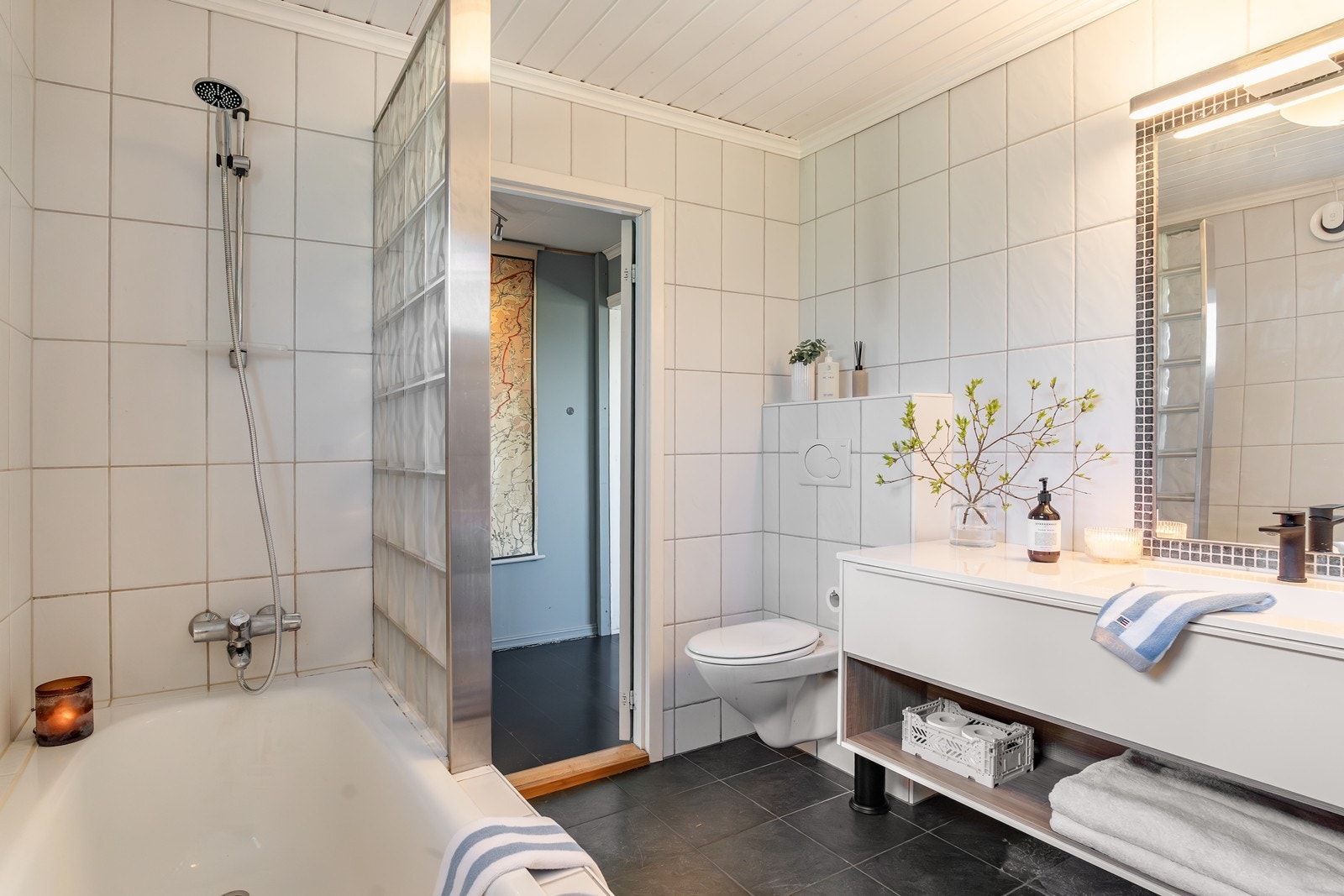 Det inneholder servant i møblement, speil m/belysning, vegghengt toalett og innebygget badekar med dusj. Galleribilde