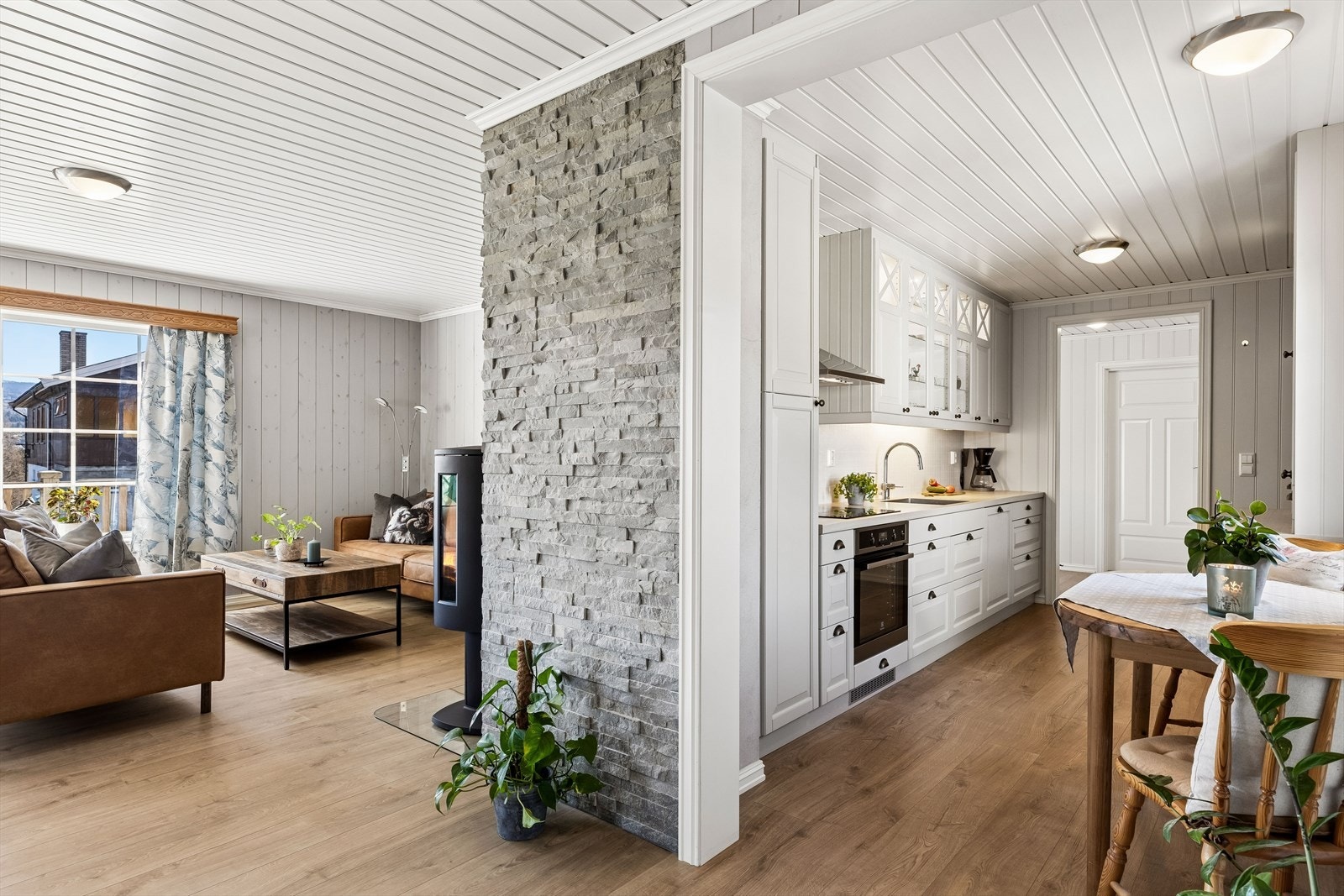 En fondvegg med steinpanel skaper en stilig overgang mellom stue og kjøkken. Galleribilde
