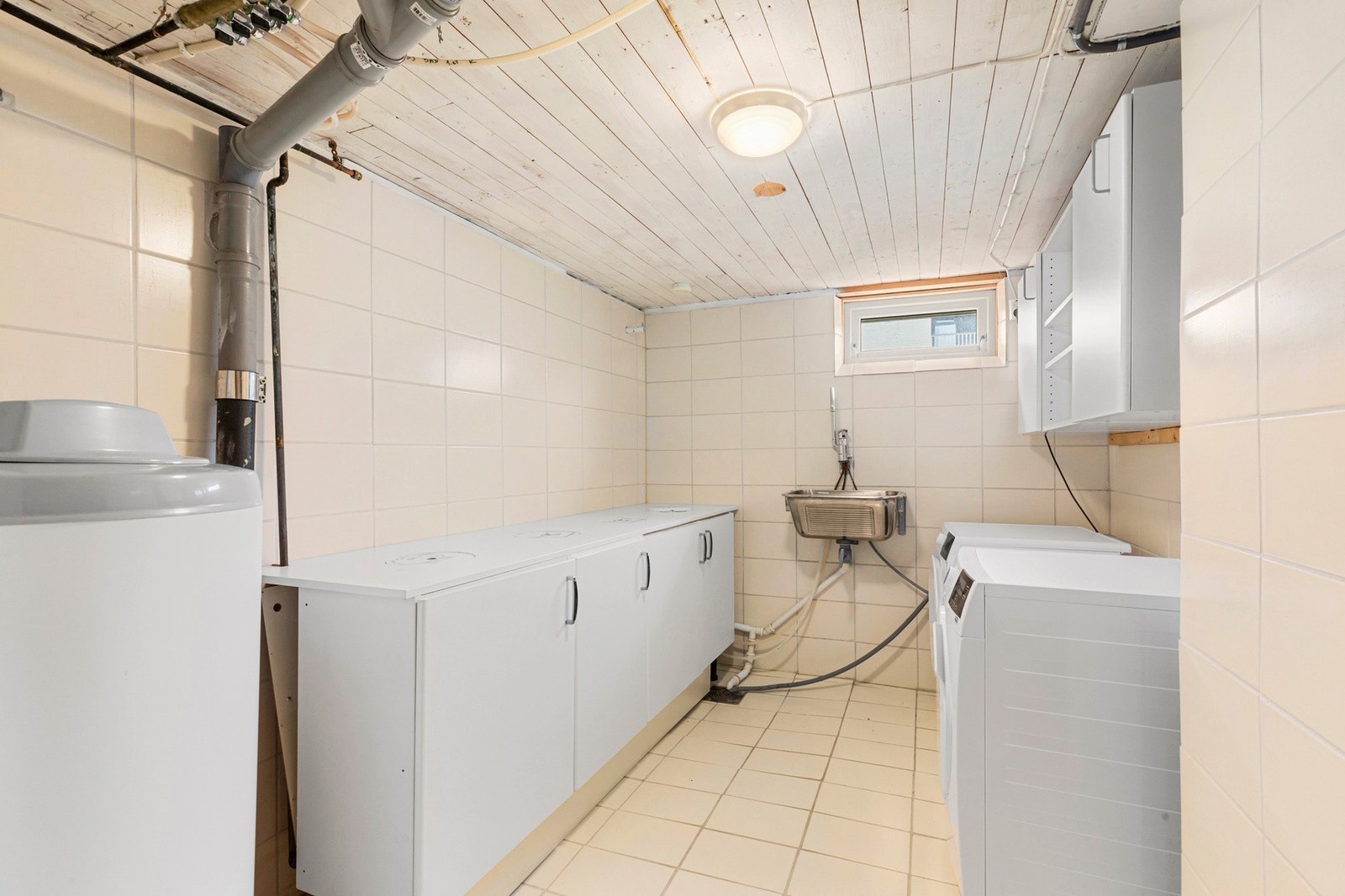 Flislagt vaskerom i kjeller med opplegg for vaskemaskin, skyllekum, stoppekran og bereder. Galleribilde