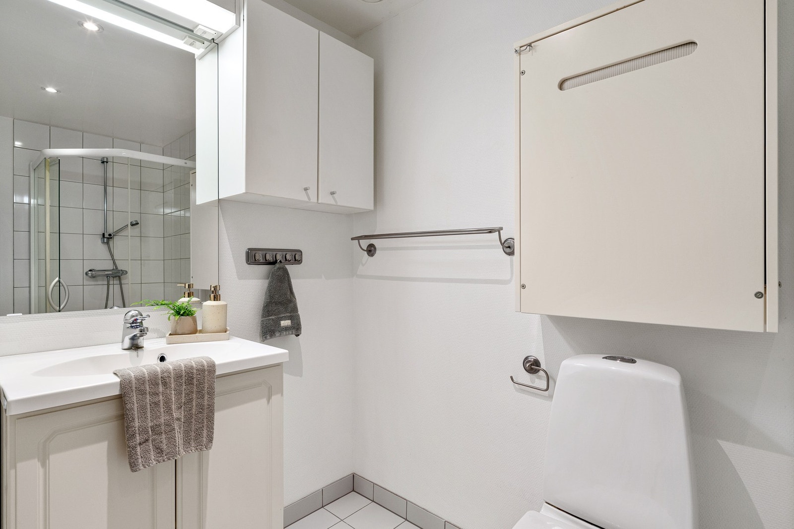Badet har en funksjonell utforming med flislagt gulv og dusjsone, samt malte vegger. Galleribilde