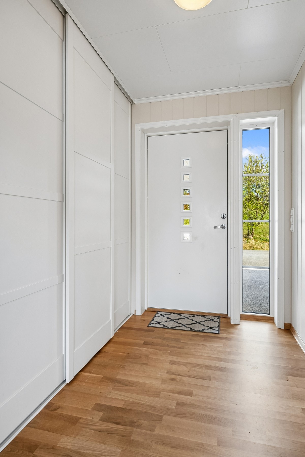 Lys og innbydande entré med stor skyvedørsgarderobe Galleribilde