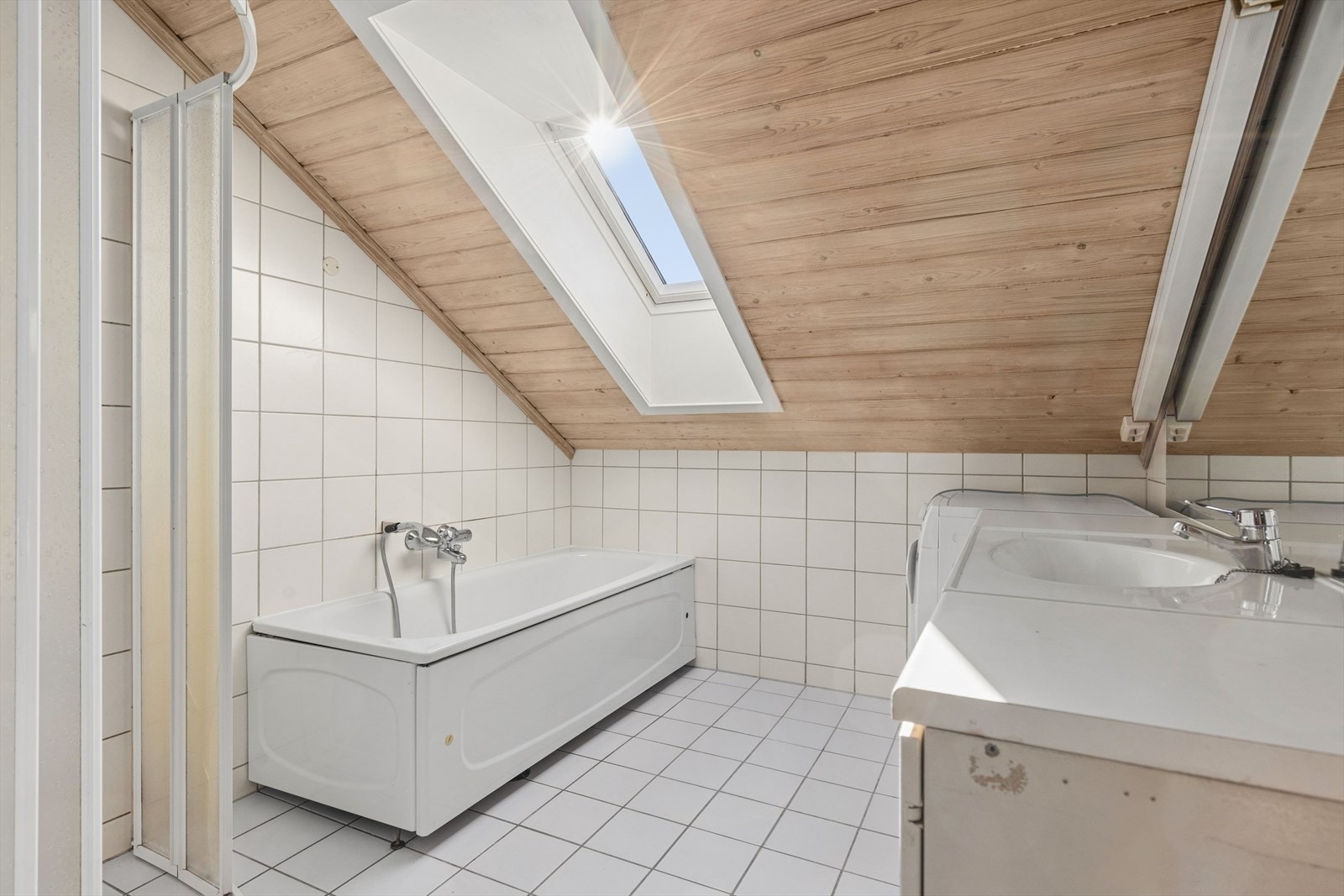 Badet i andre etasje er flislagt og utstyrt med badekar, opplegg for vaskemaskin og varmekabler i gulvet. Galleribilde