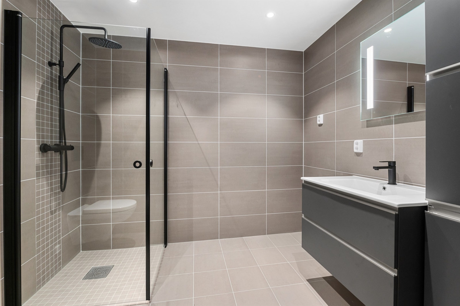Badet inneholder blant annet servantskap, speil med innebygd lys, vegghengt toalett, opplegg for vaskemaskin og downlights i himling. Galleribilde