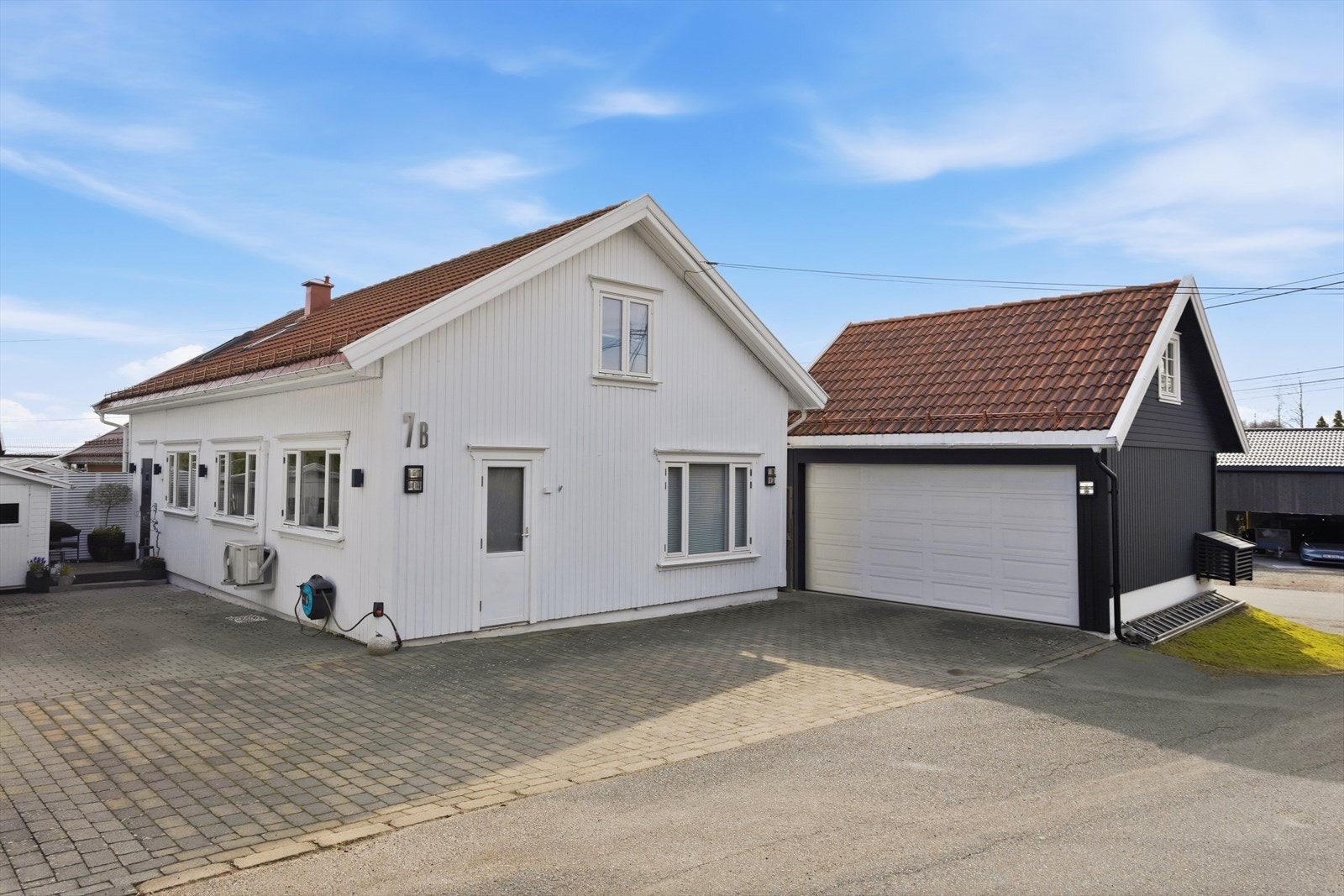 Fasaden med inngangspartiet og gårdsplassen med garasje m/isolert hems. Galleribilde
