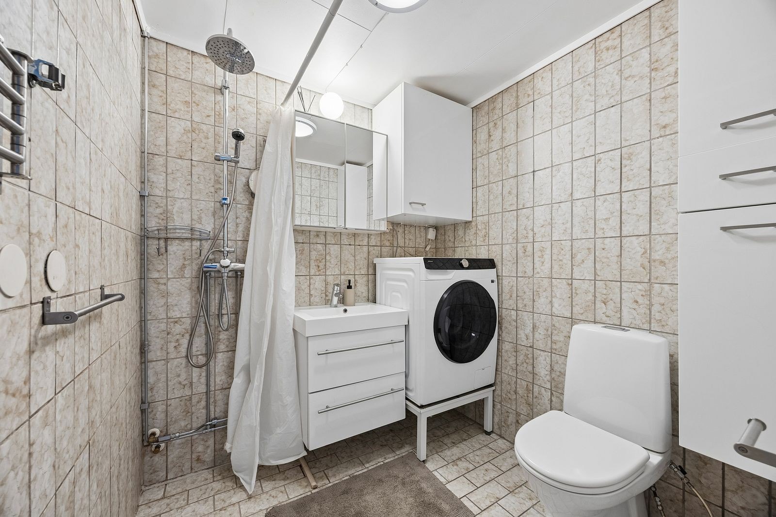 Badet er eldre men har varmekabler i gulv. Kombinert vaskemaskin og tørketrommel Galleribilde