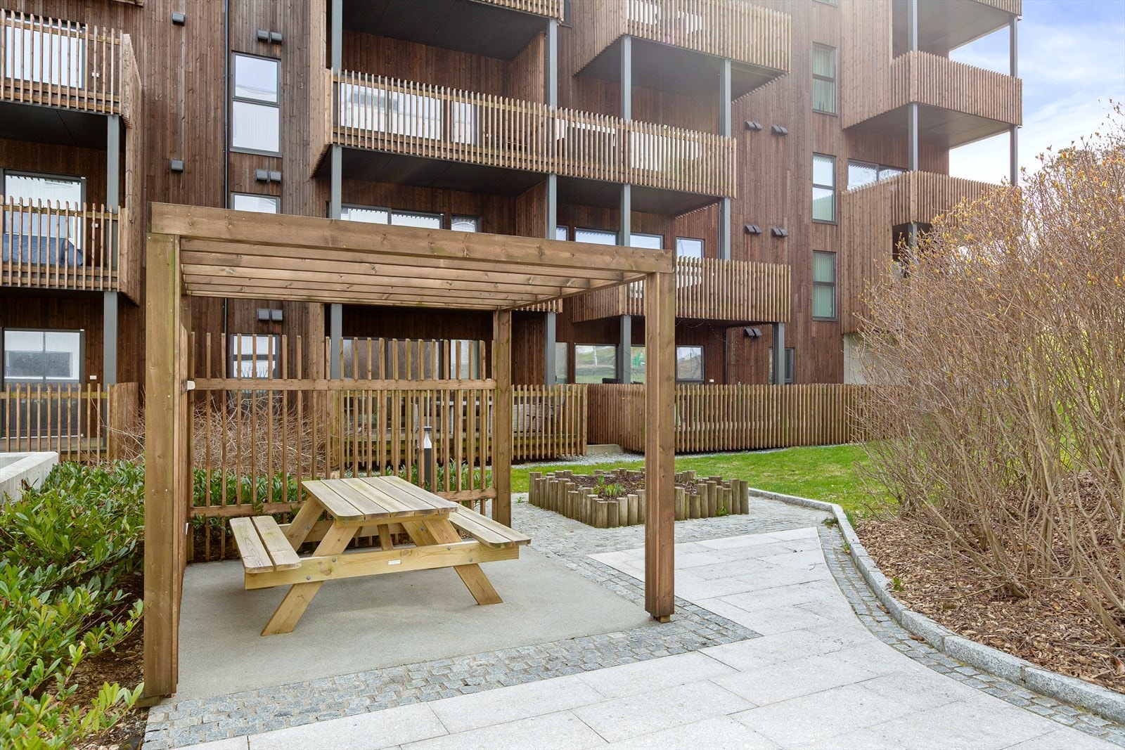 Pent opparbeidet fellestomt med beplanting, grøntareal og asfaltert gårdsrom. Det er opparbeidet med lekeapparater på sørsiden. Galleribilde
