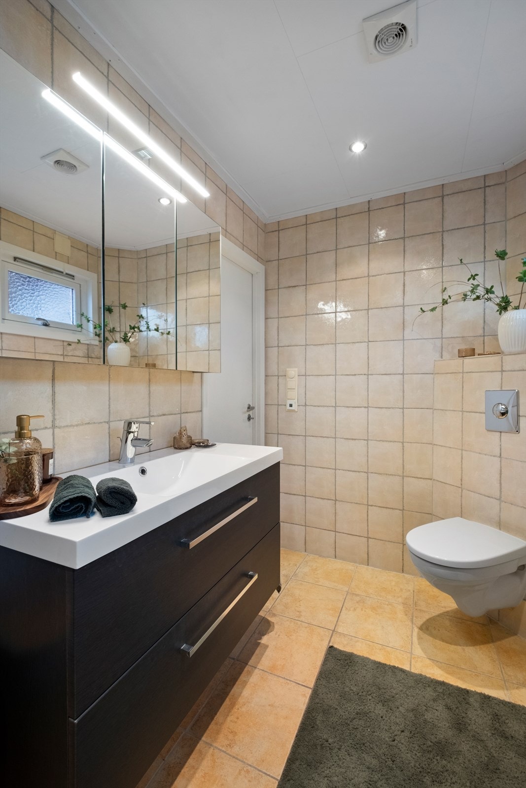 Badet er helfliset og er utstyrt med en romslig innredning m/servant og speilskap samt vegghengt wc - Galleribilde