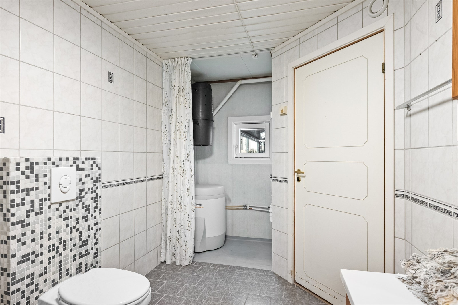 Badet har en praktisk nisje med opplegg for vaskemaskin og plass til varmtvannsbereder. Galleribilde