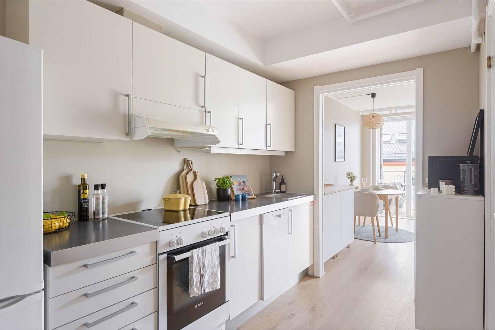 Pen kjøkkeninnredning antatt fra 2006 med glatte folierte fronter, laminat benkeplate med nedfelt kum i rustfritt stål og ventilator tilsluttet kanal/ventilasjonssystem. Galleribilde